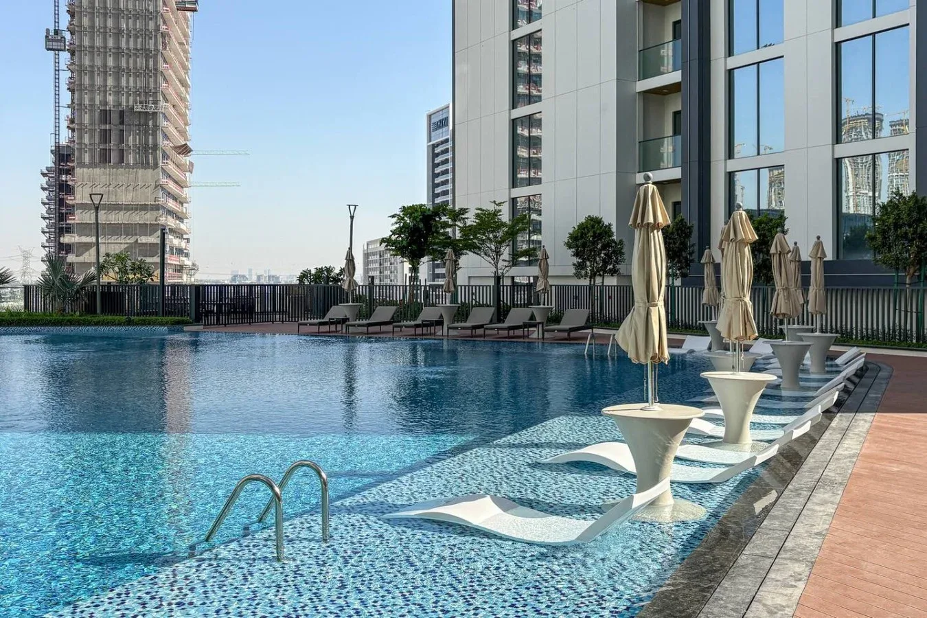 Una piscina al aire libre junto a un edificio moderno, con asientos junto al borde.