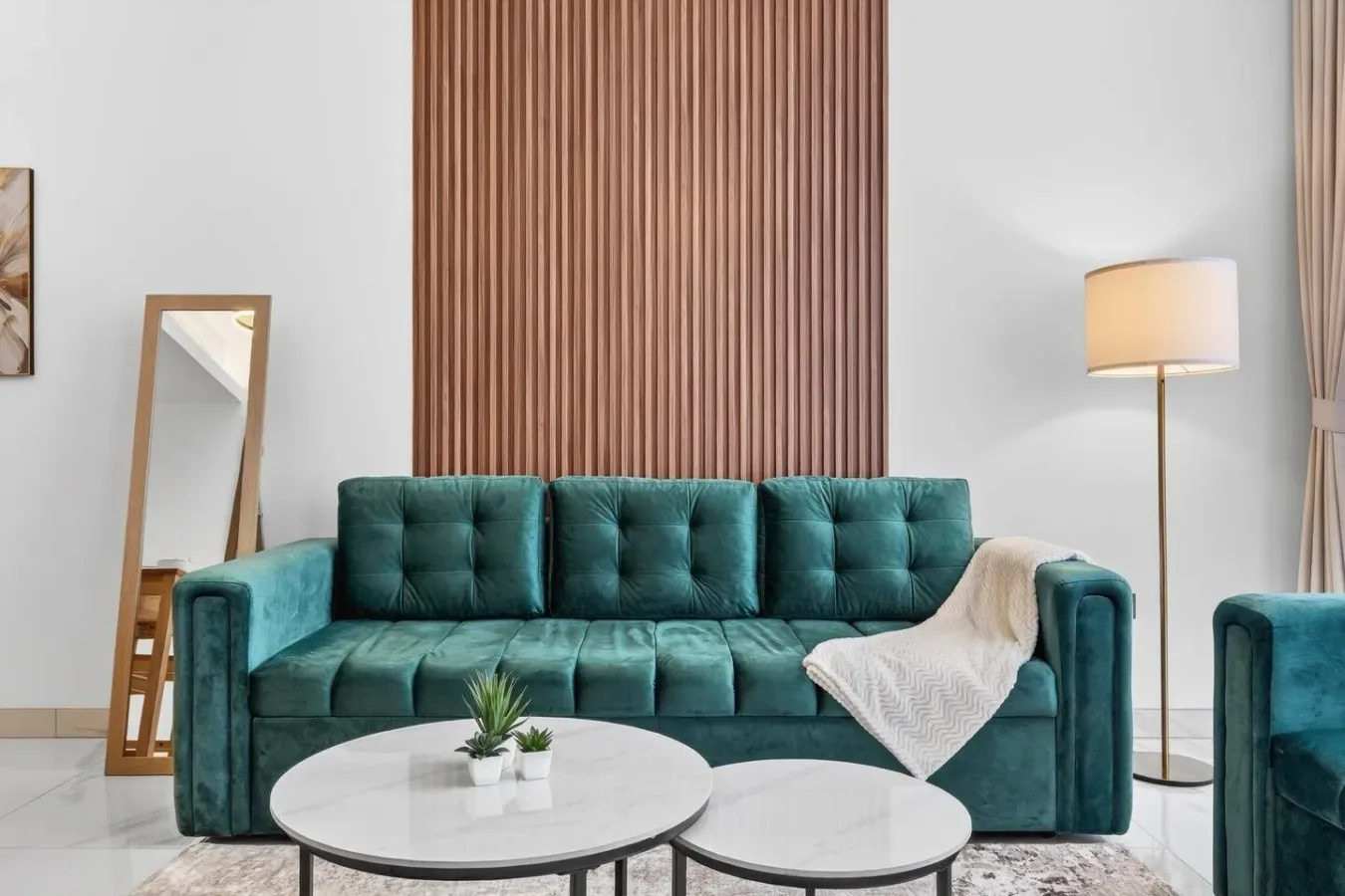 Una sala de estar con asientos color turquesa, una mesa de centro redonda y una lámpara de pie.