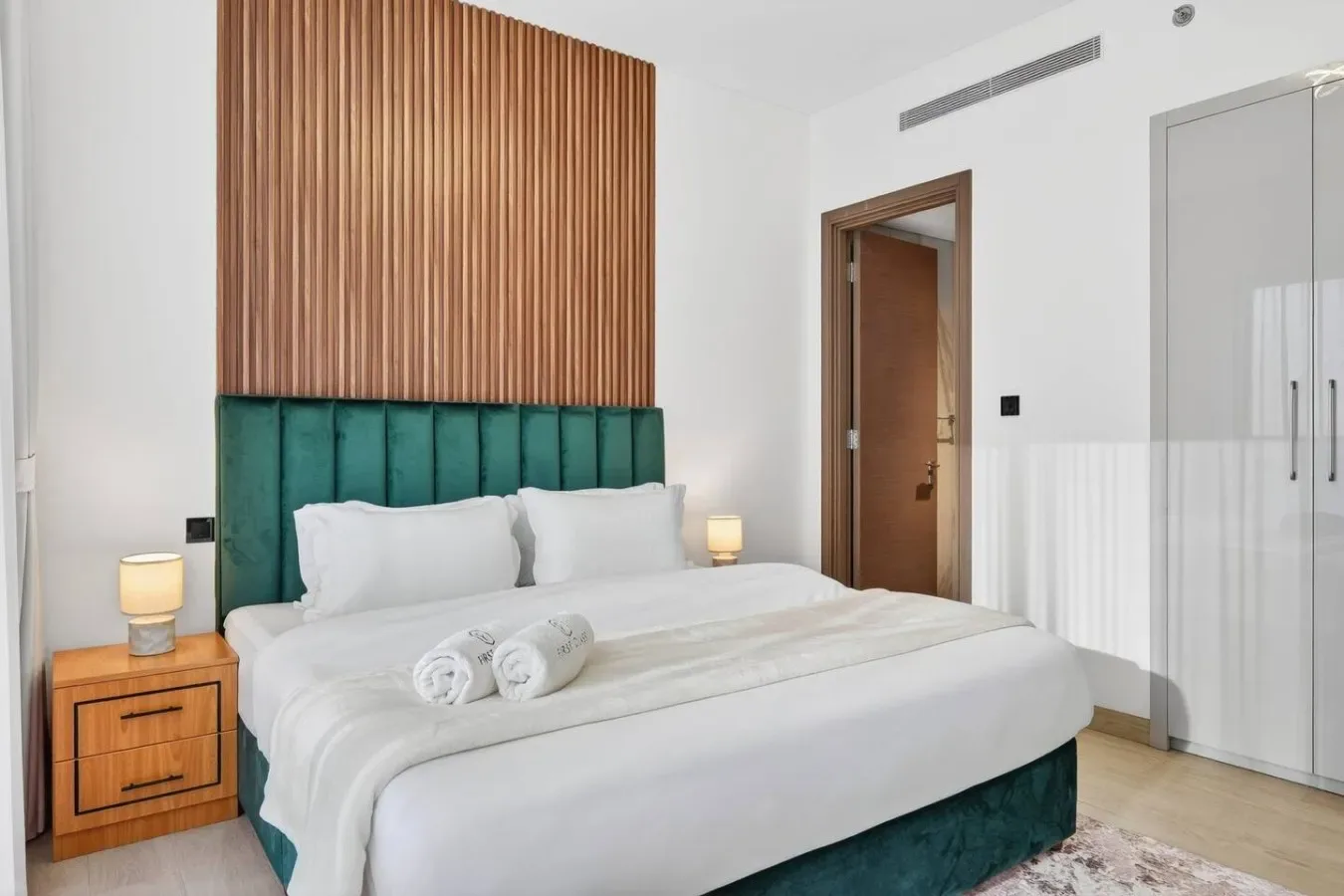 Un dormitorio con una cama bien tendida y una mesita de madera.