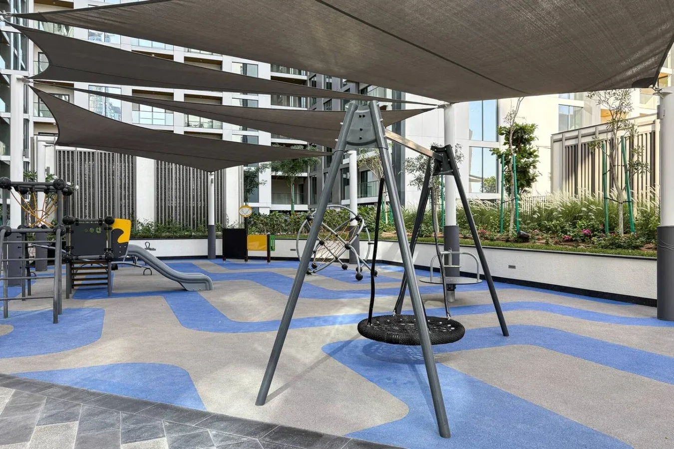 Un área de juegos al aire libre con estructuras para trepar bajo toldos de sombra.