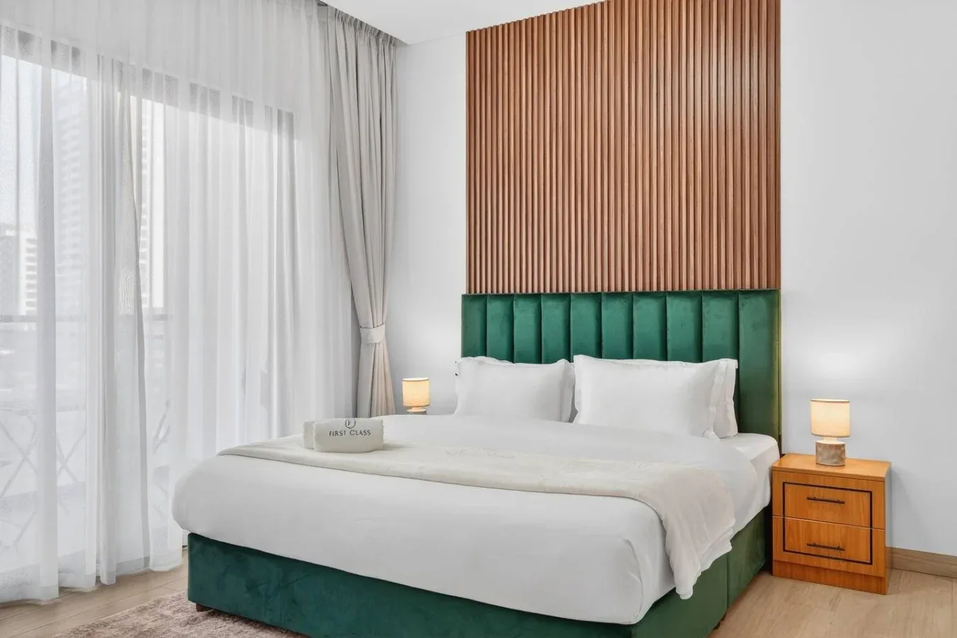 Un dormitorio con una cama tapizada en verde bajo una pared de listones de madera.