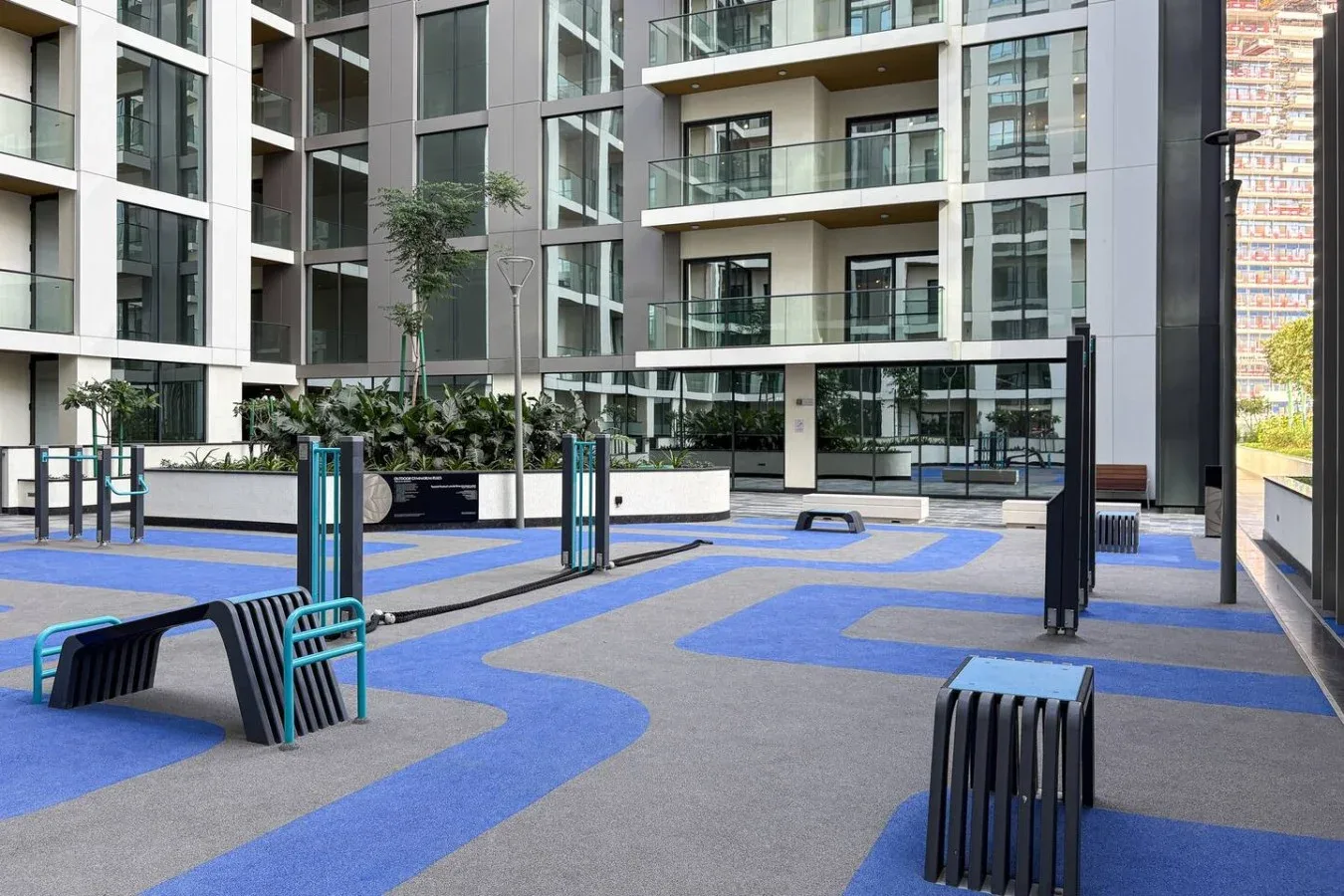 Un patio con pavimento azul y gris y edificios de apartamentos modernos.