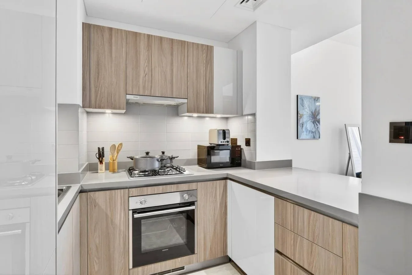 Una cocina moderna con gabinetes de madera clara, una placa de cocina y un horno empotrado.