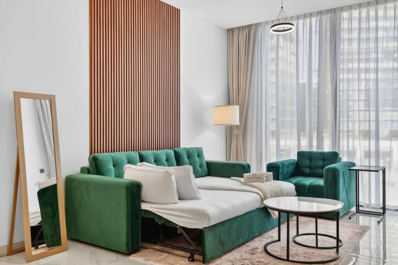 Una sala de estar con asientos verdes, una mesa de centro y cortinas translúcidas.