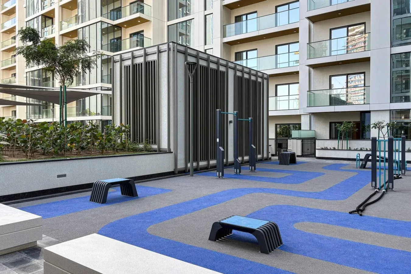 Una zona de ejercicio al aire libre con equipos está rodeada de edificios de apartamentos modernos.