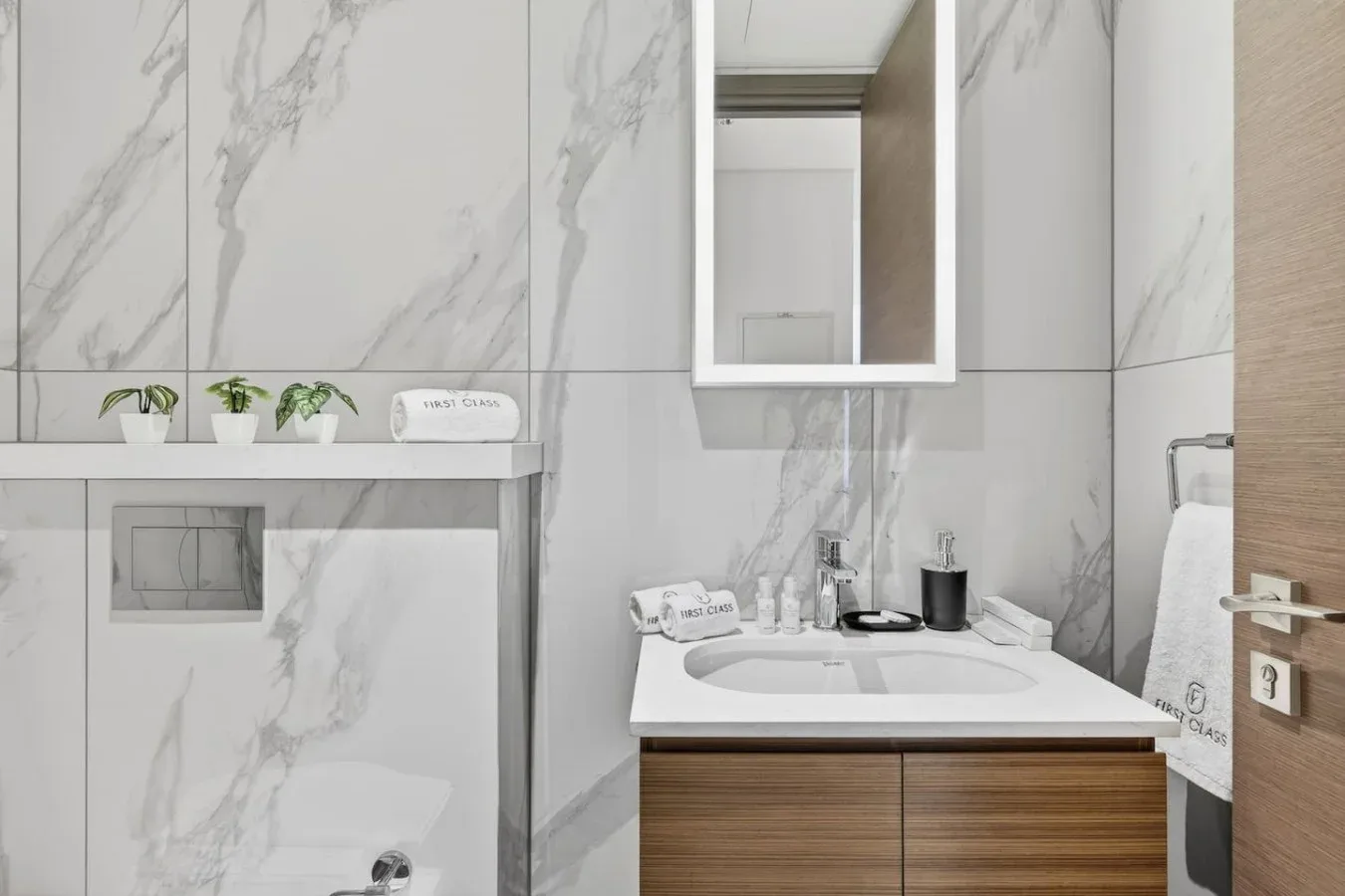 Un baño moderno con lavabo, espejo de pared y zona de ducha alicatada.