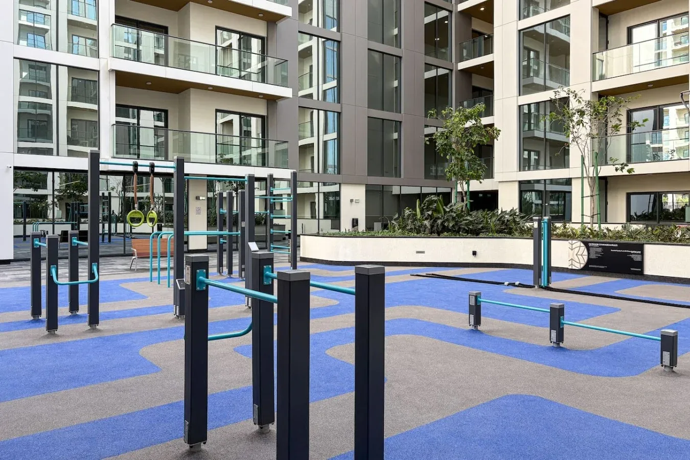 Una zona de ejercicio al aire libre con equipos frente a un edificio de apartamentos moderno.