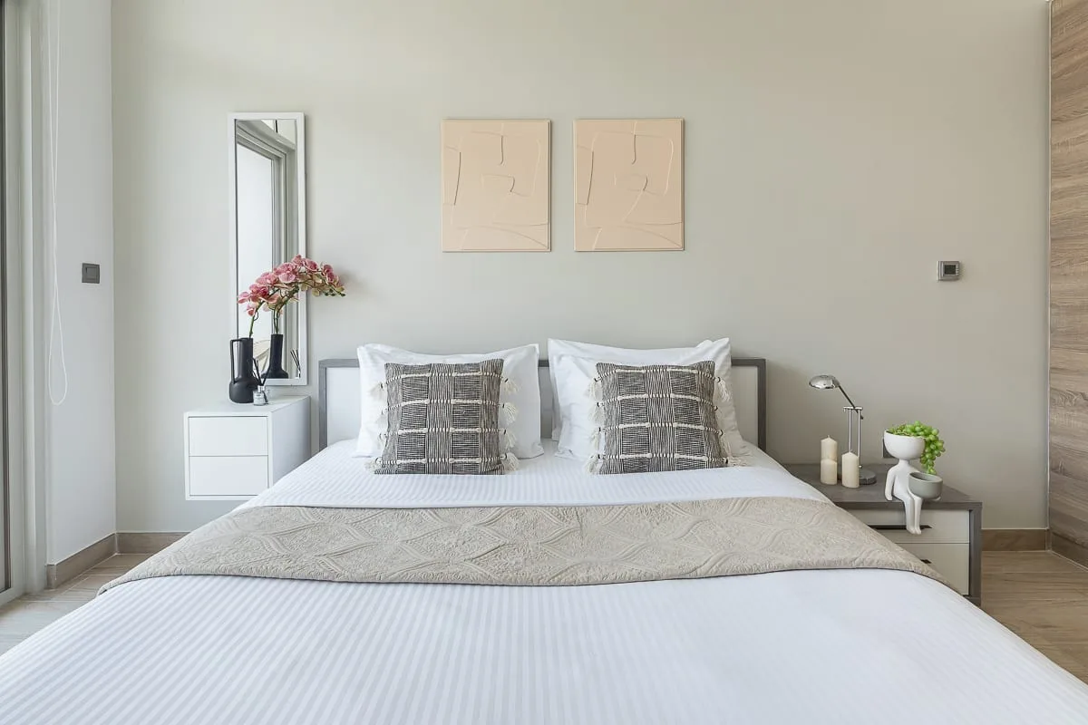 A bedroom with a bed, patterned pillows, and simple artwork above the headboard.