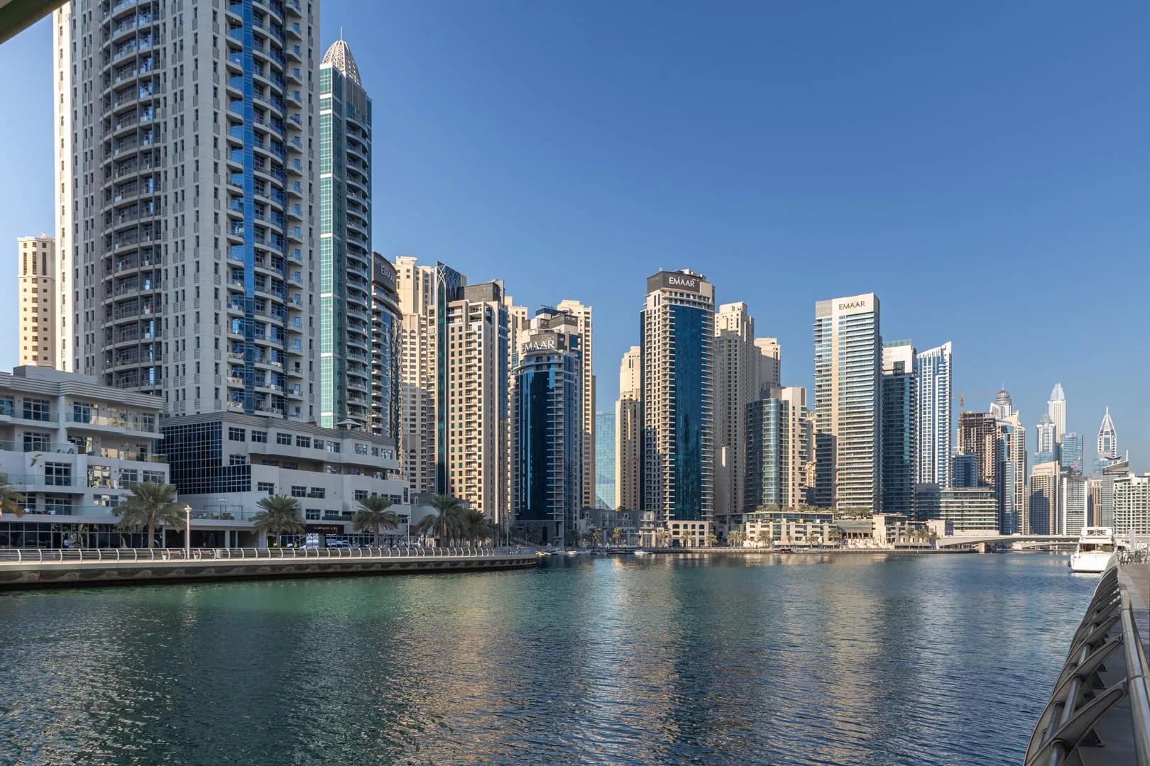 A waterfront skyline of tall modern buildings rises above the calm canal.