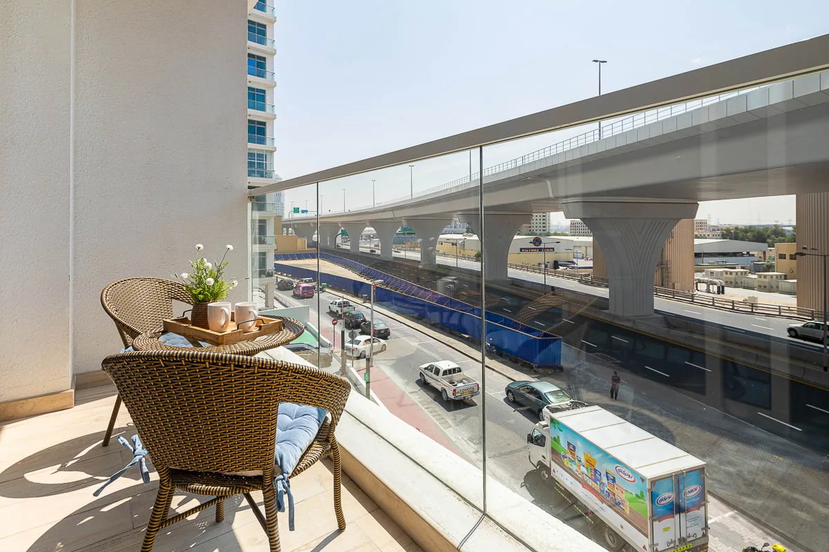 A balcony seating area overlooks a road beneath an elevated roadway.