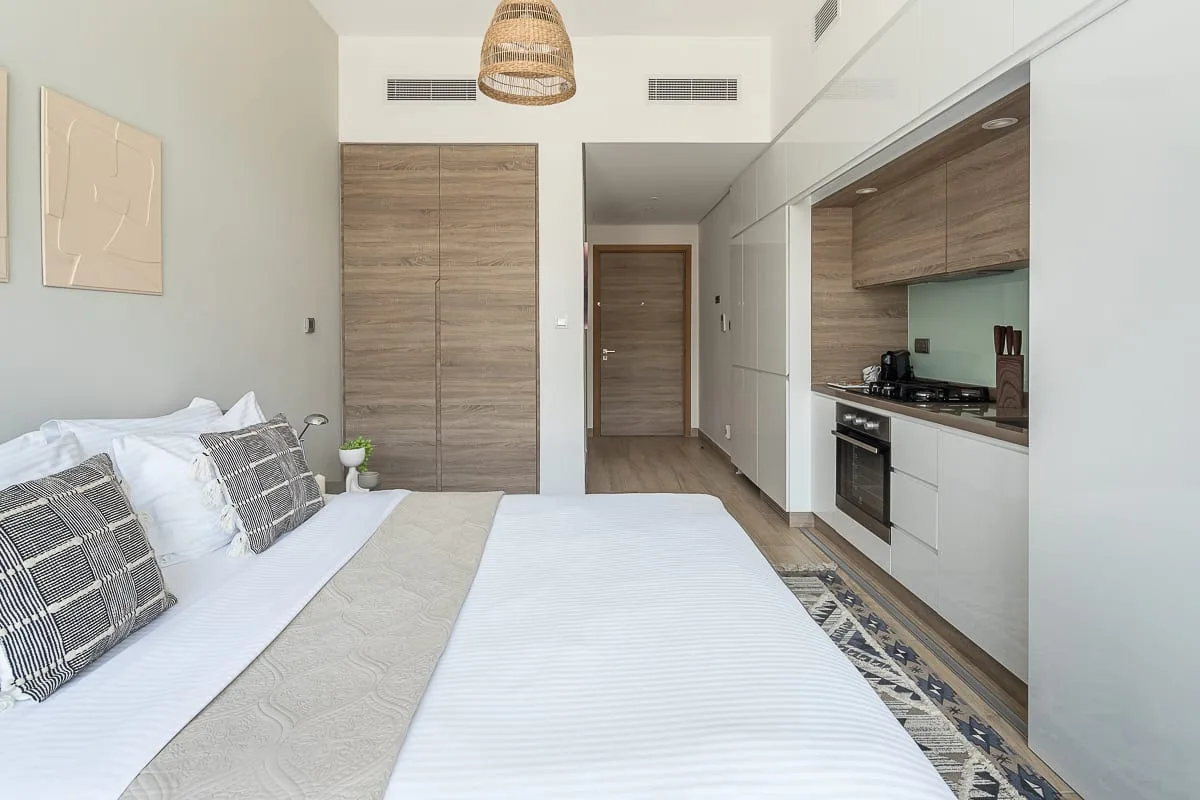 Un dormitorio luminoso con una cama junto a una pequeña cocina.