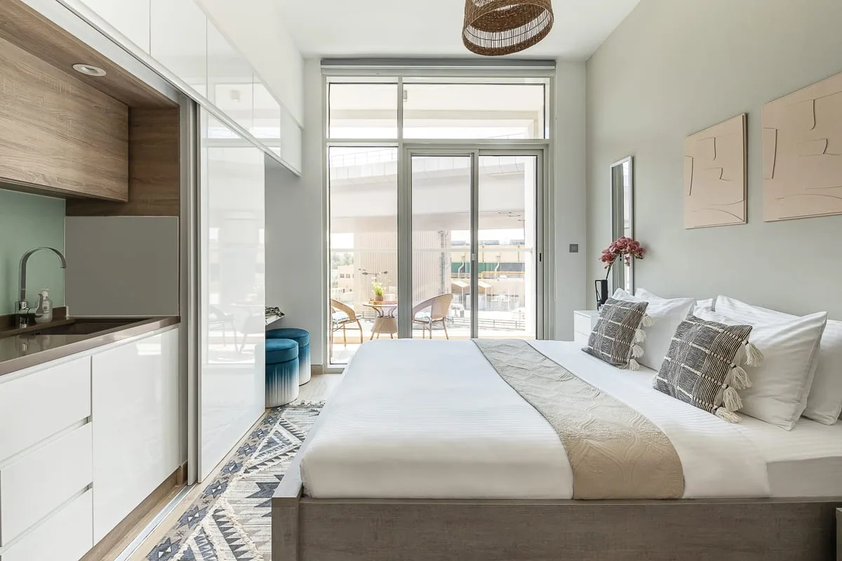 Un dormitorio luminoso con una cama grande junto a puertas de vidrio de piso a techo.