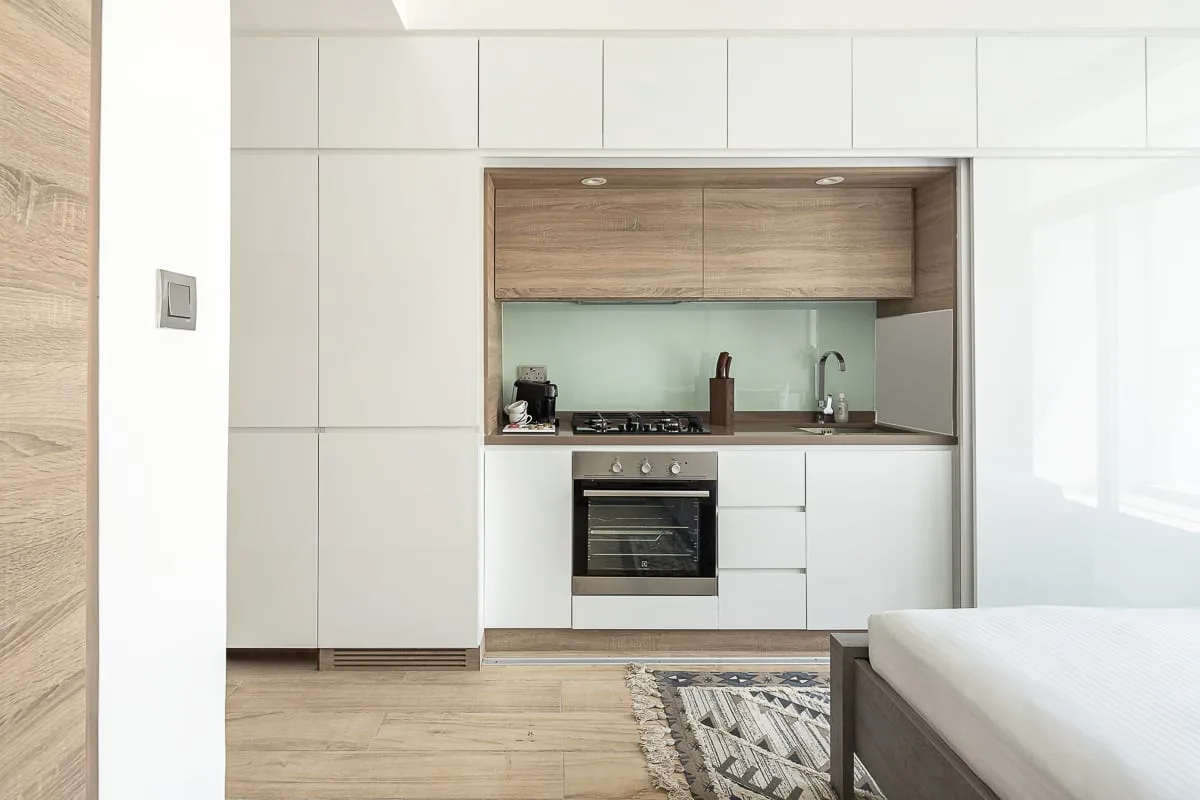 Una cocina moderna con gabinetes blancos, horno empotrado y suelo de madera.