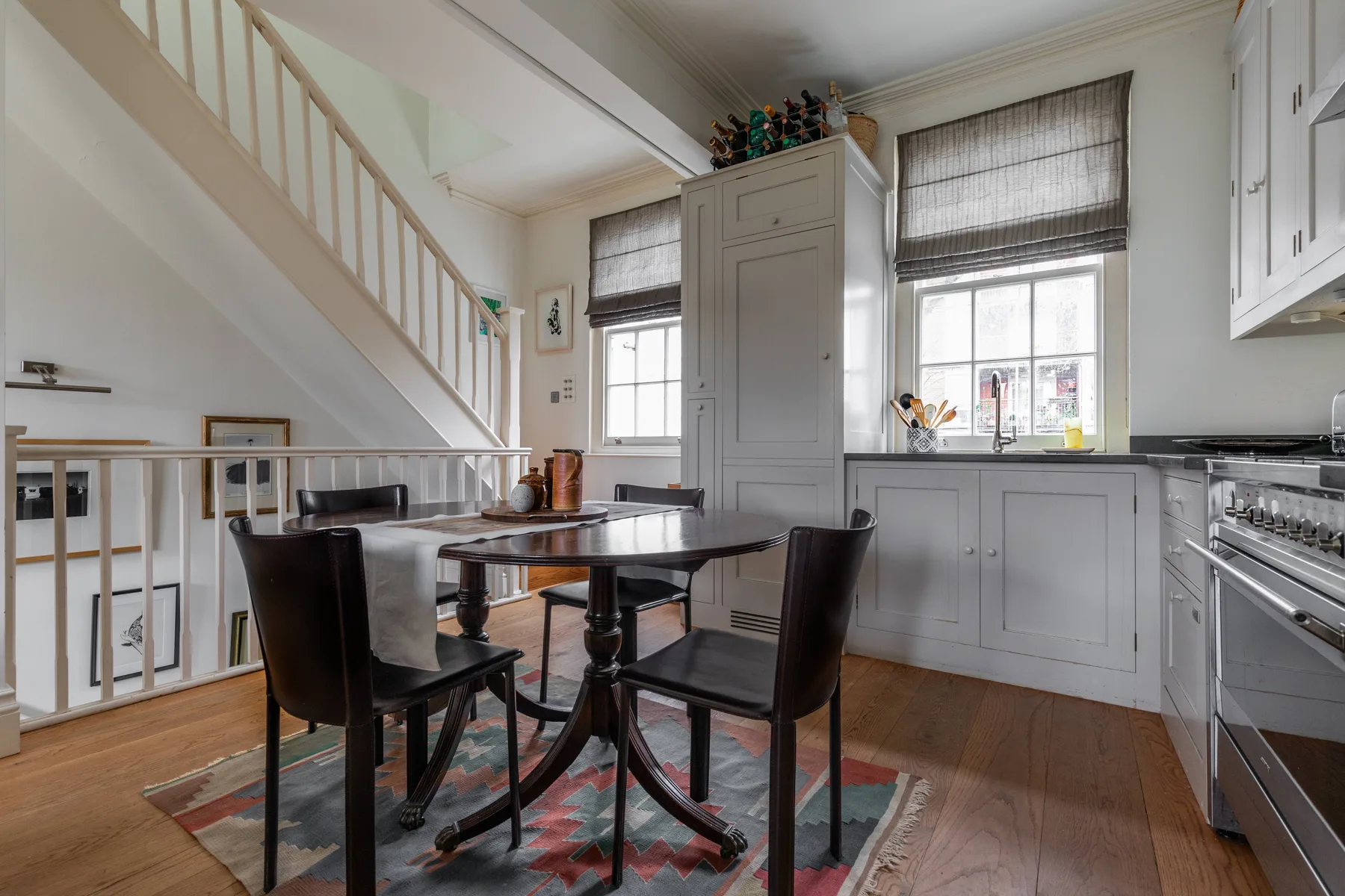 A dining area with a dark table and chairs beside a bright kitchen.
