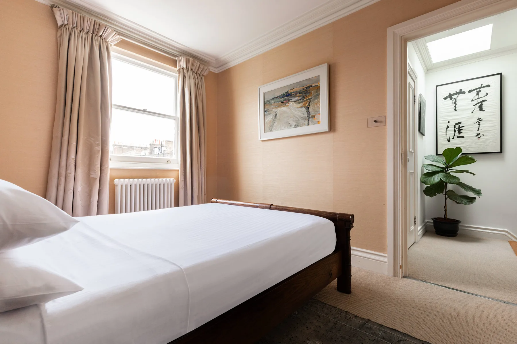 A bedroom with a bed beside a curtained window and radiator.