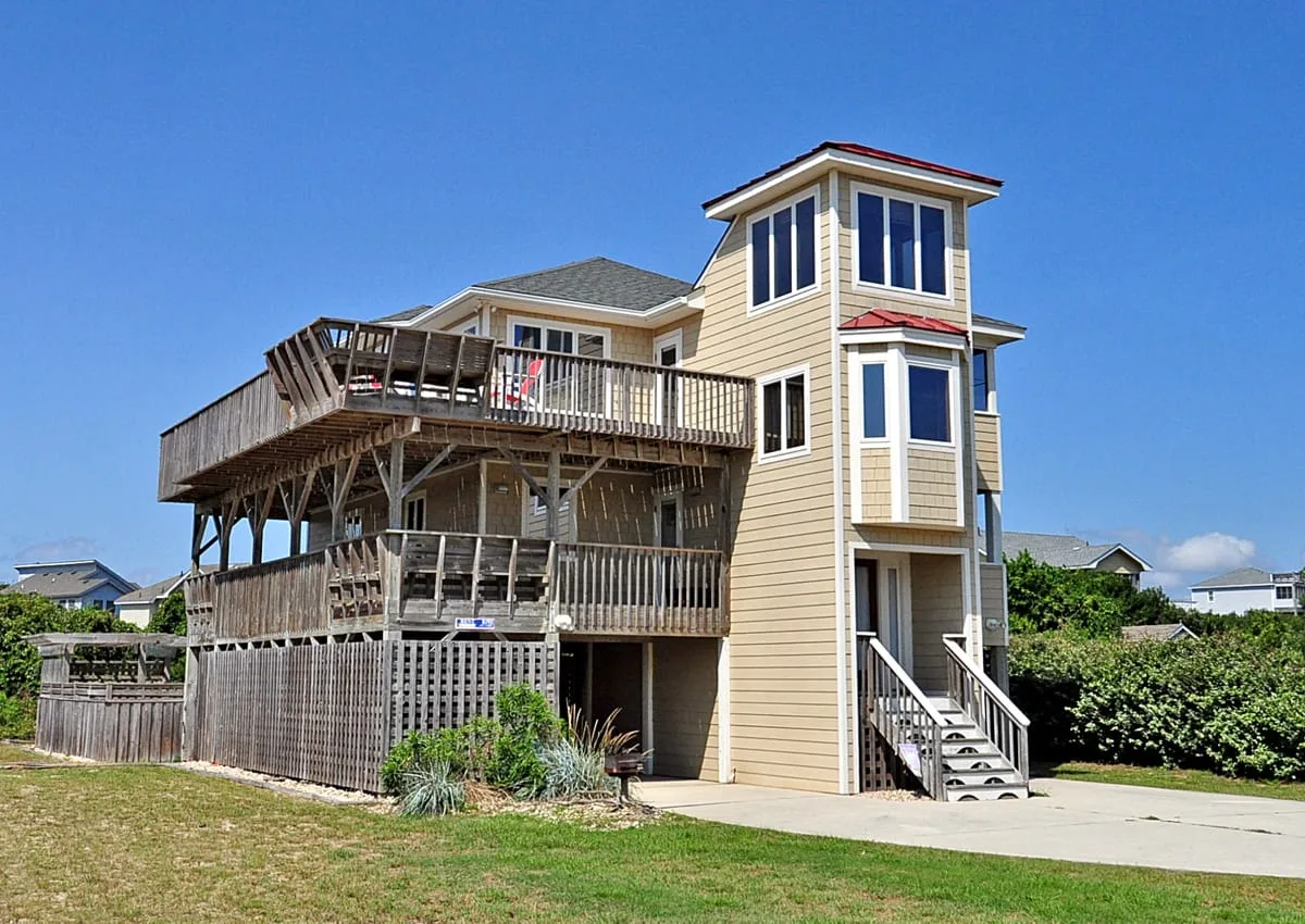 Una casa elevada de estilo costero con terrazas de madera y una escalera exterior.