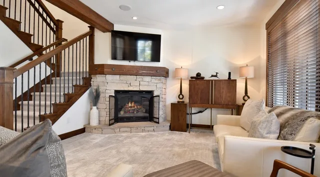 Una sala de estar con chimenea de piedra, televisor y escalera.