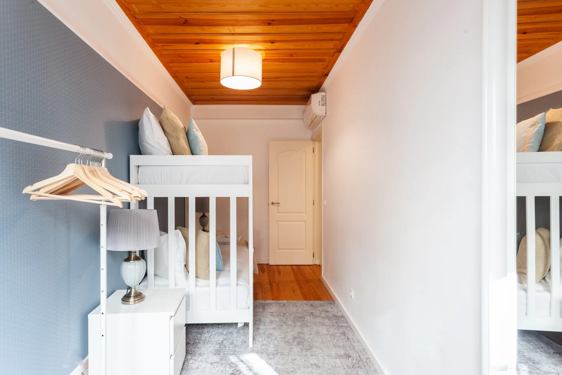 A bedroom with a white bed, a wardrobe, and a wooden ceiling.