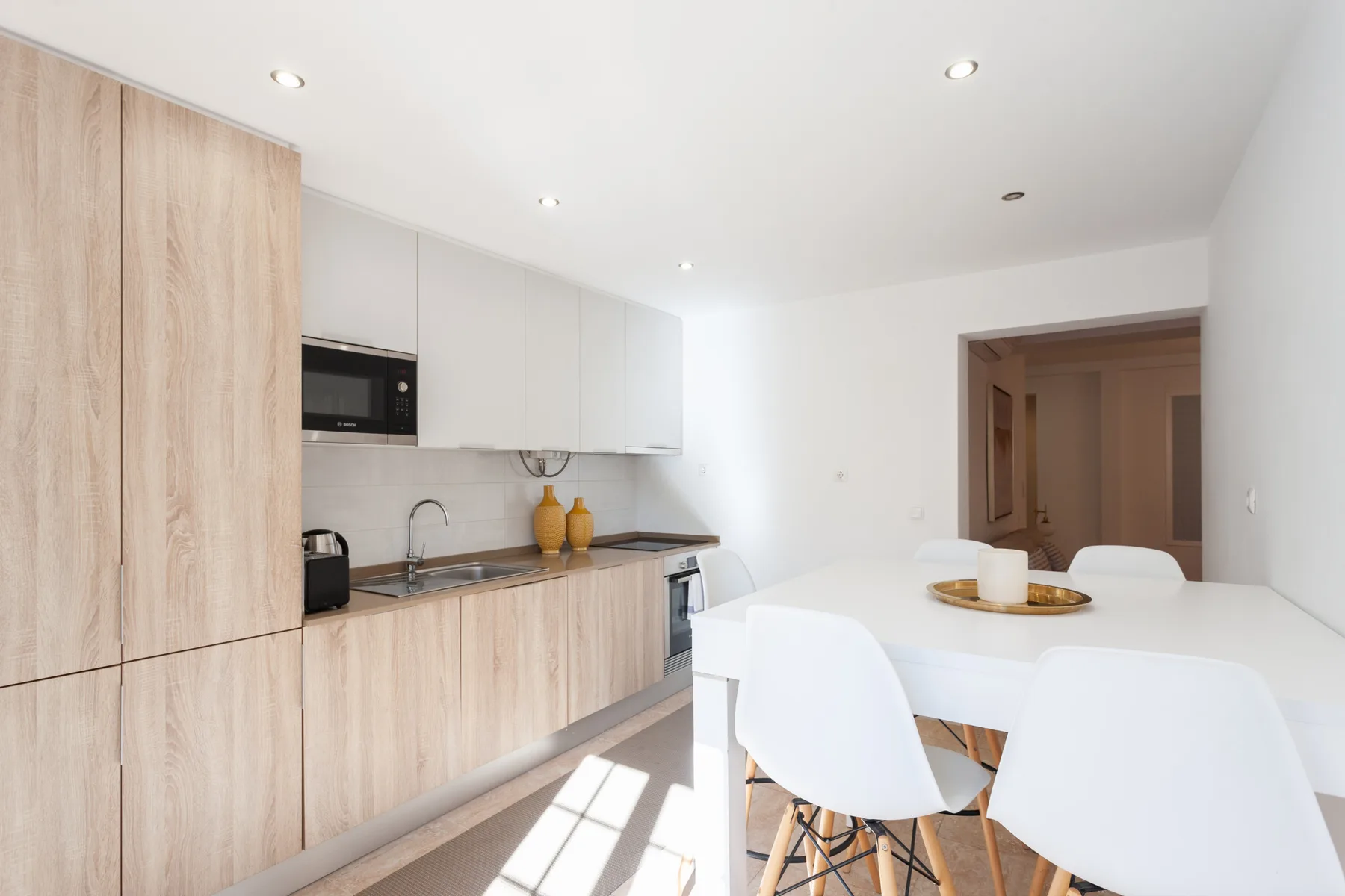 A bright kitchen and dining area with light wood cabinets and a white table.