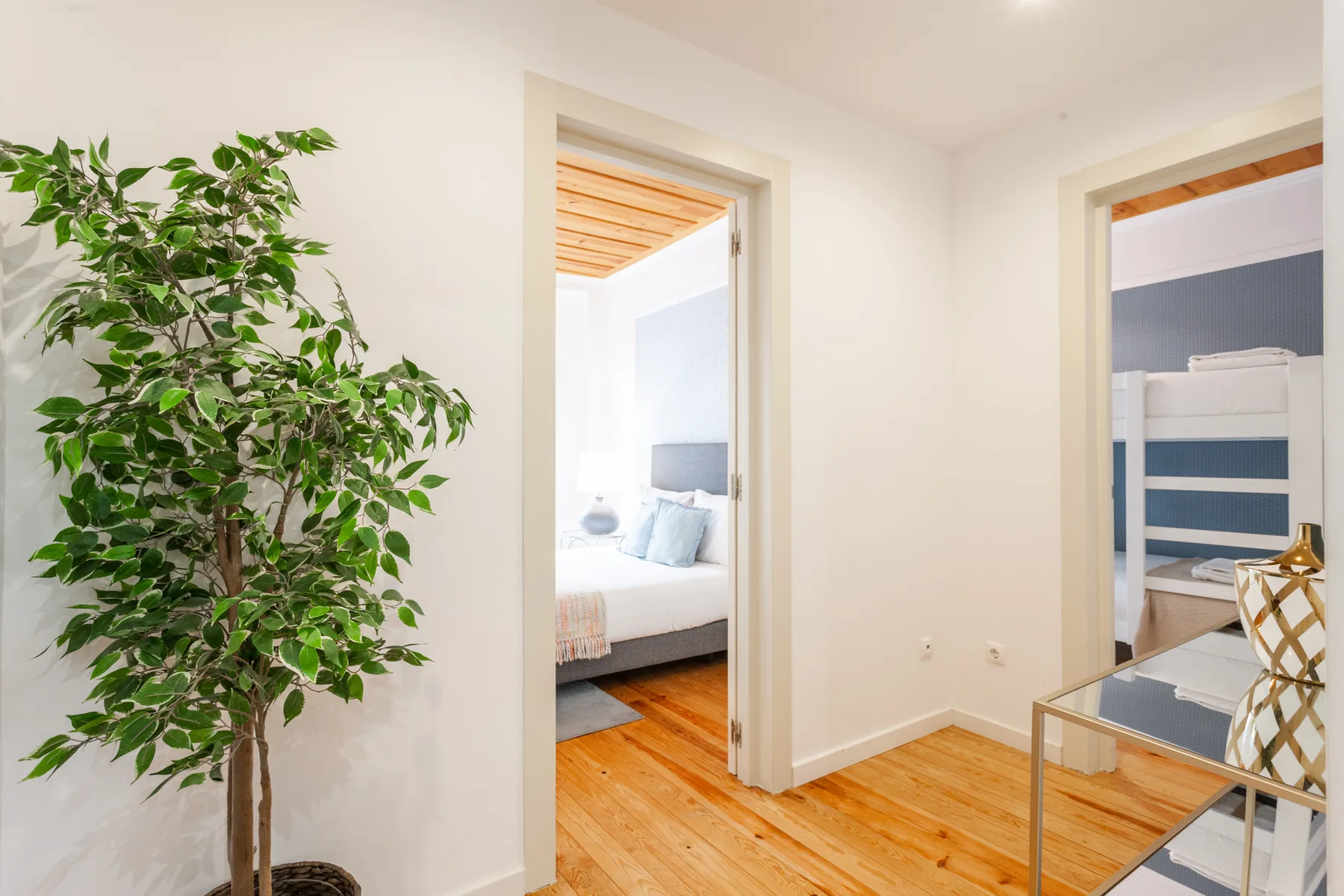 A bright hallway opens onto a bedroom and a room with bunk beds.