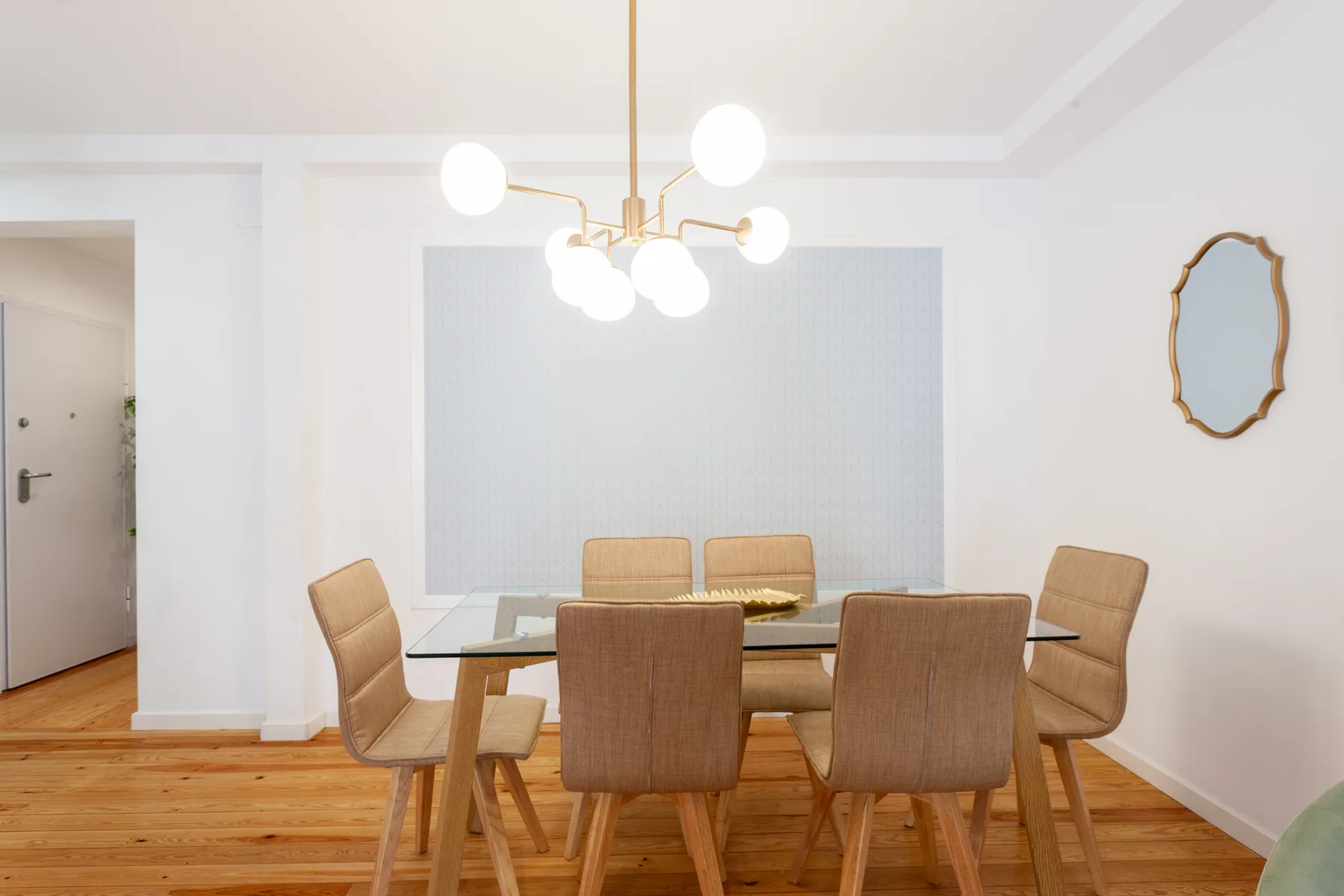 A dining area with a table and upholstered seating beneath a hanging light.