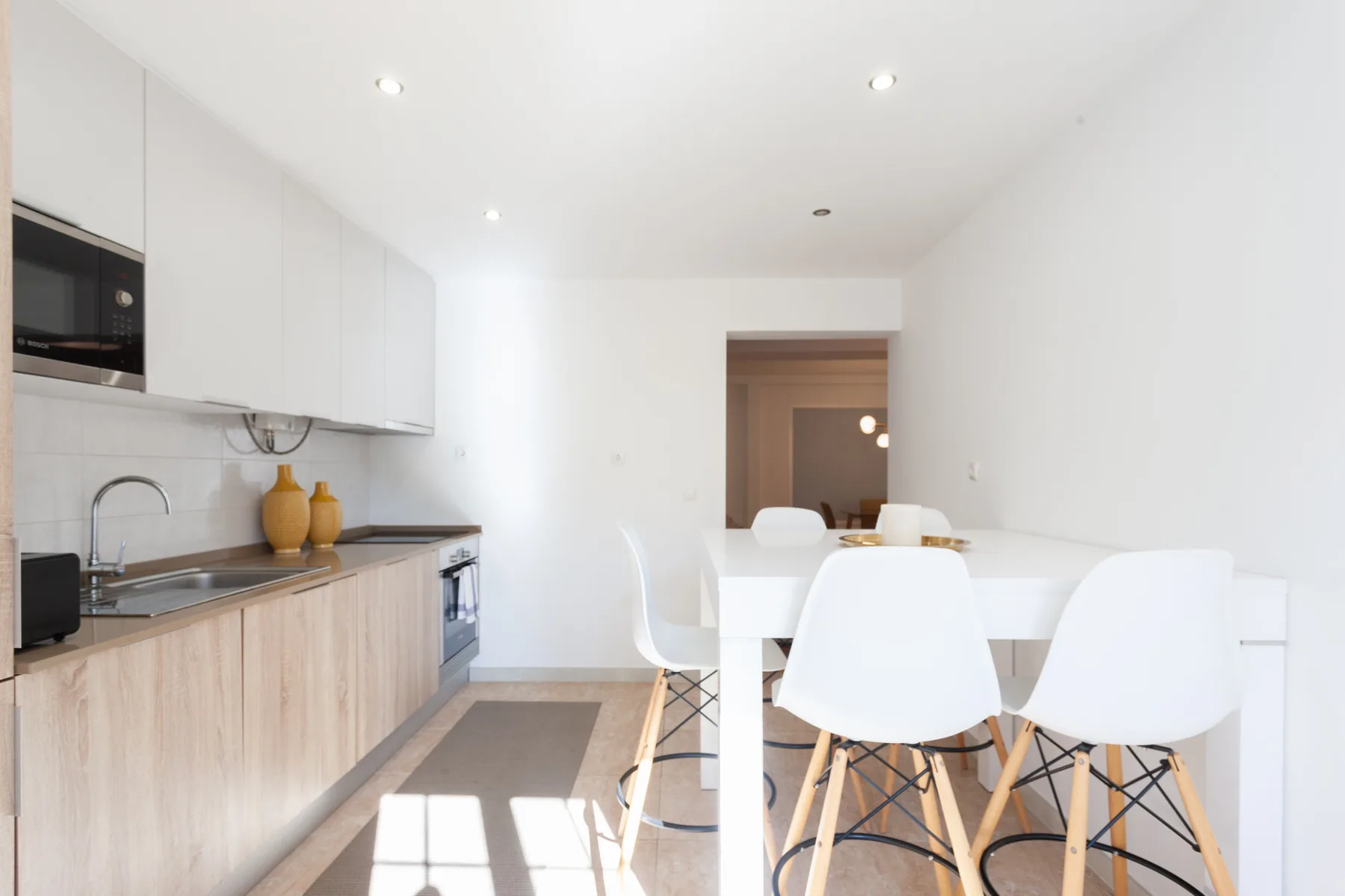 A bright kitchen and dining area with white seating and a long counter.