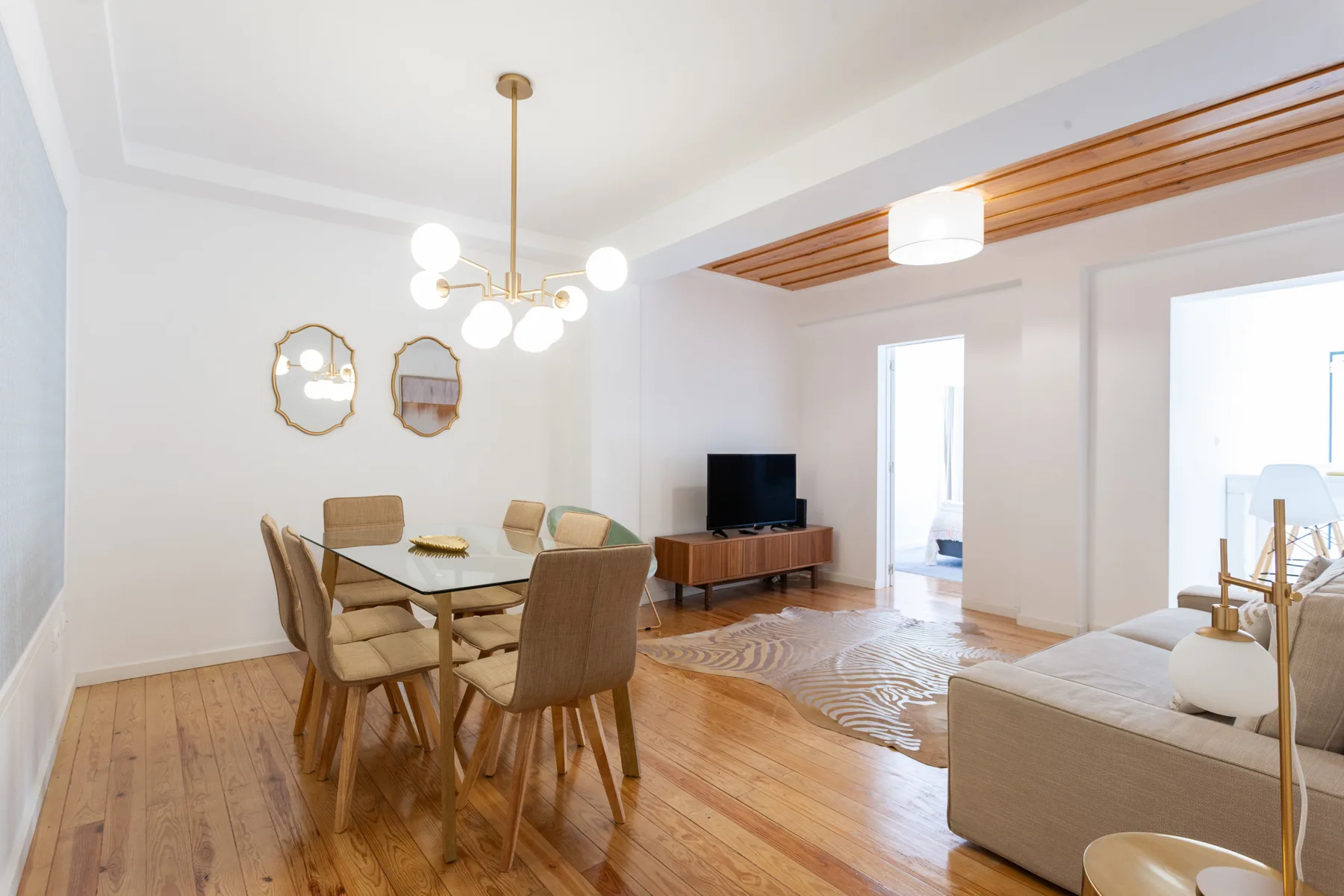 A bright living and dining area with a table, seating, and a television.