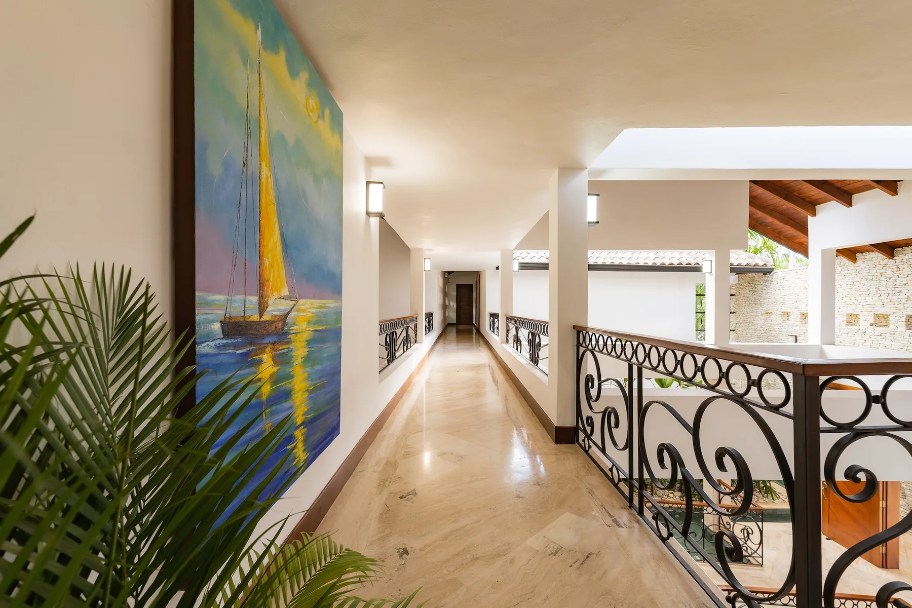 A bright indoor gallery corridor with polished flooring and decorative metal railings.