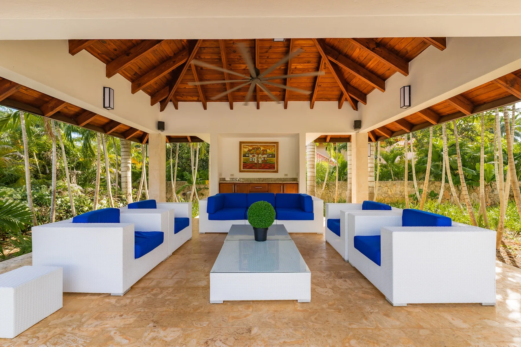 An open-sided lounge with blue-and-white seating beneath a timber roof.