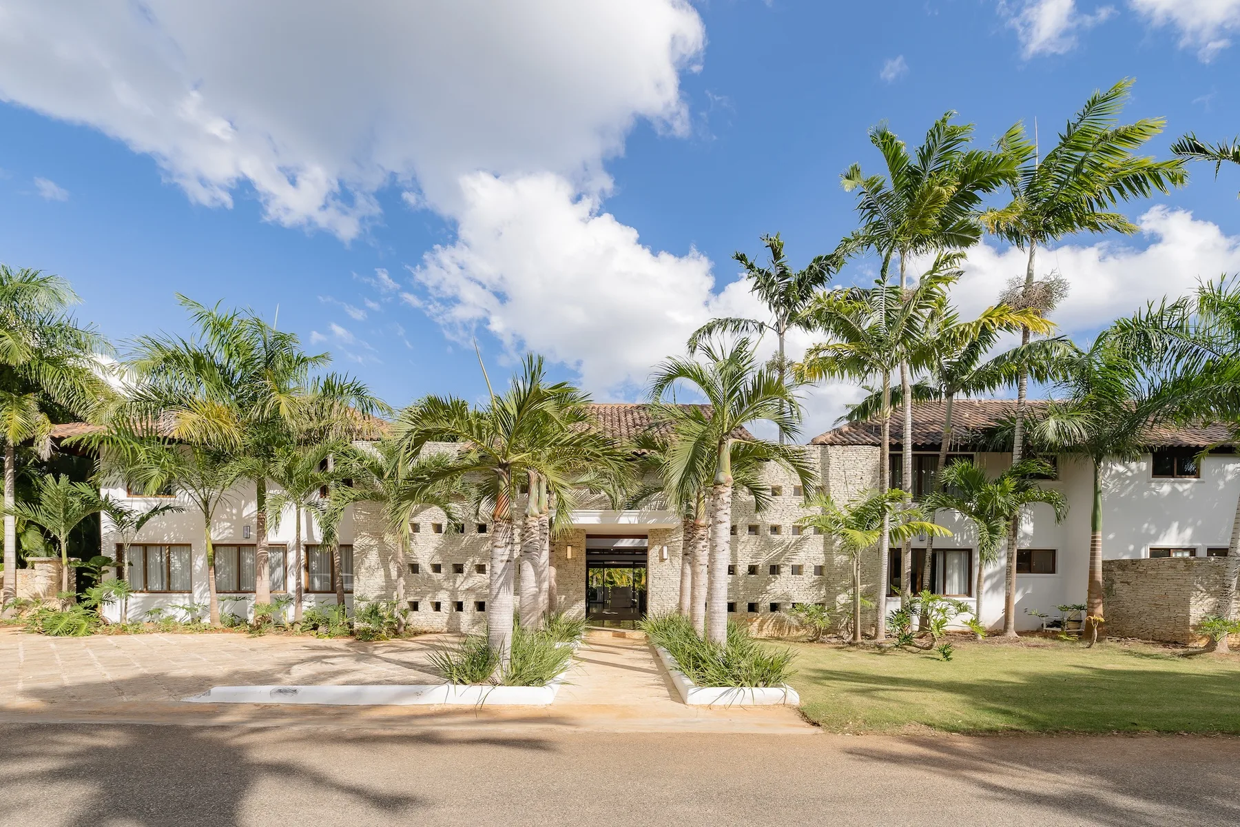 A low-rise building with stone walls and palm trees along the front.