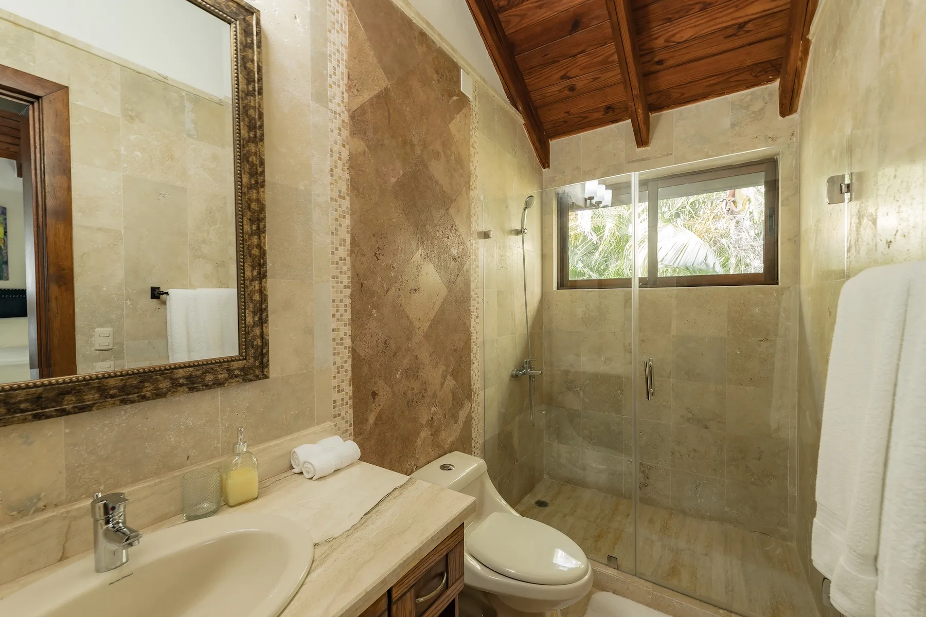 A tiled bathroom with a sink, toilet, and glass shower.