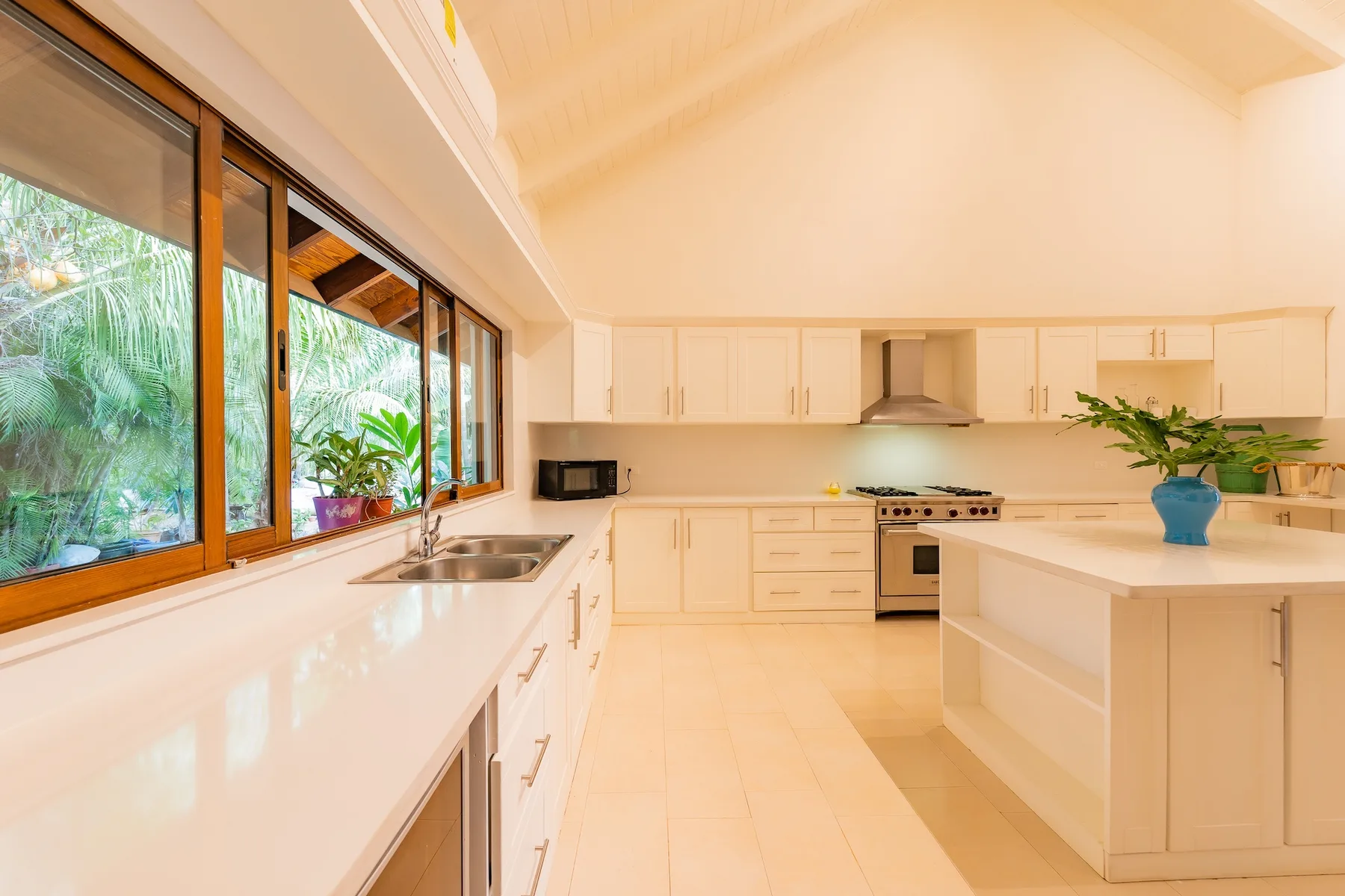 A bright kitchen with white cabinets, a central island, and large windows.