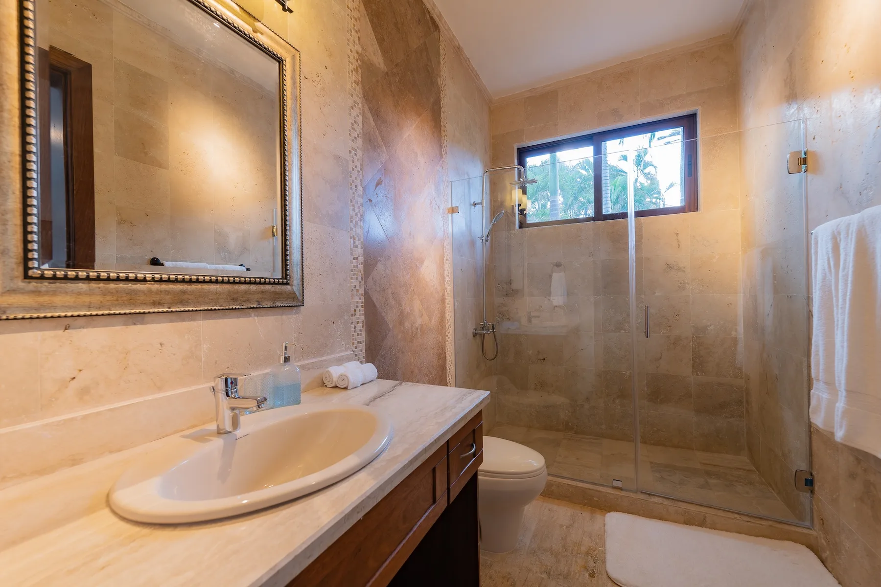 A bathroom with a vanity, toilet, and glass-enclosed shower.