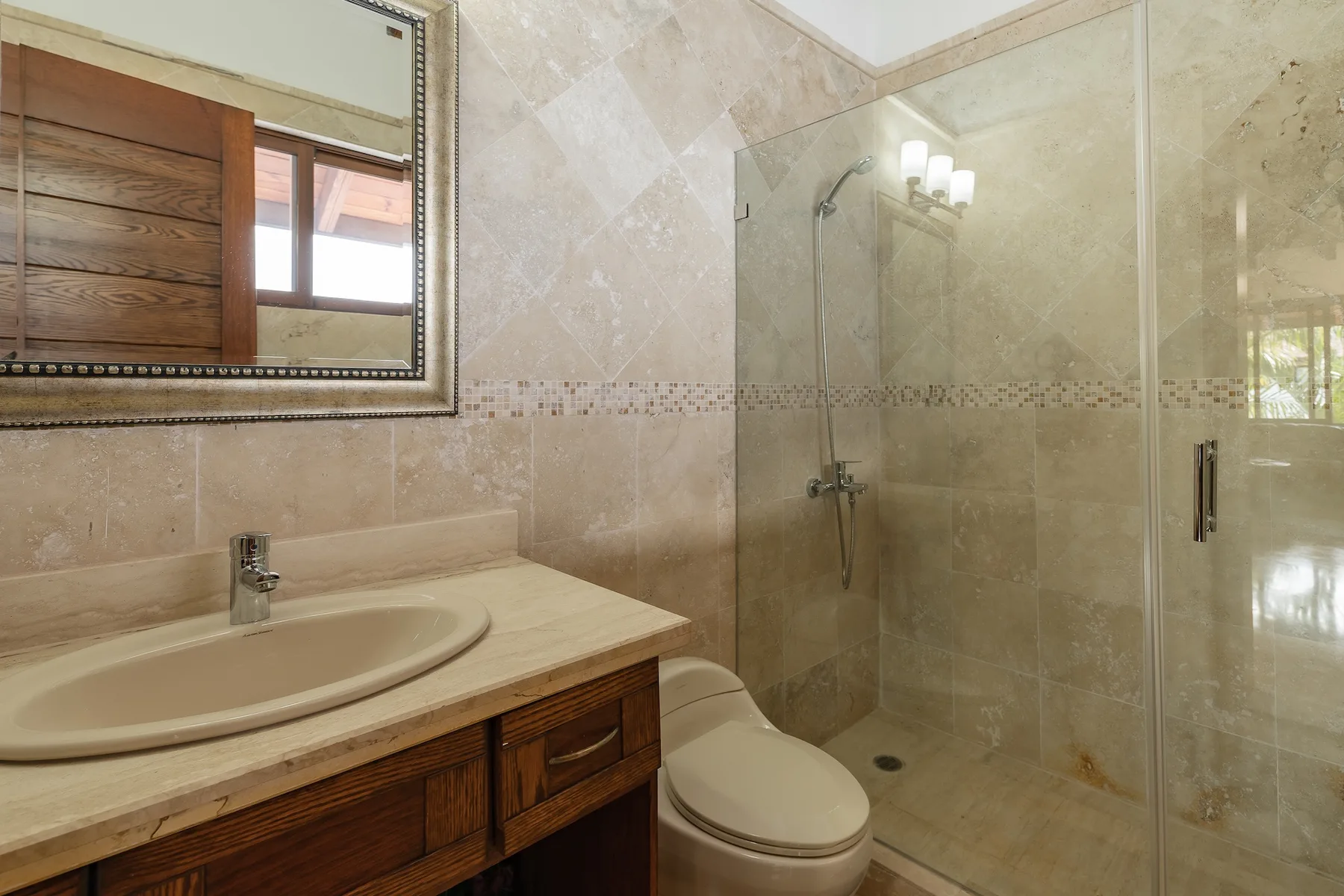 A bathroom with a vanity, toilet, and glass shower.
