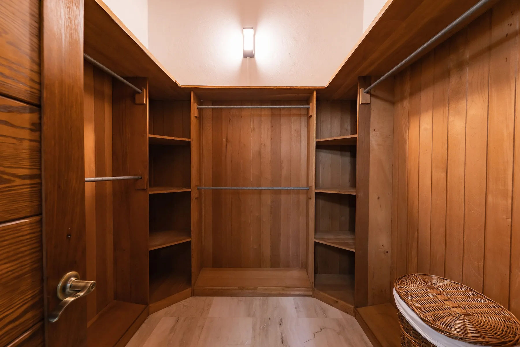 A wood-paneled walk-in closet with open shelving and hanging rails.