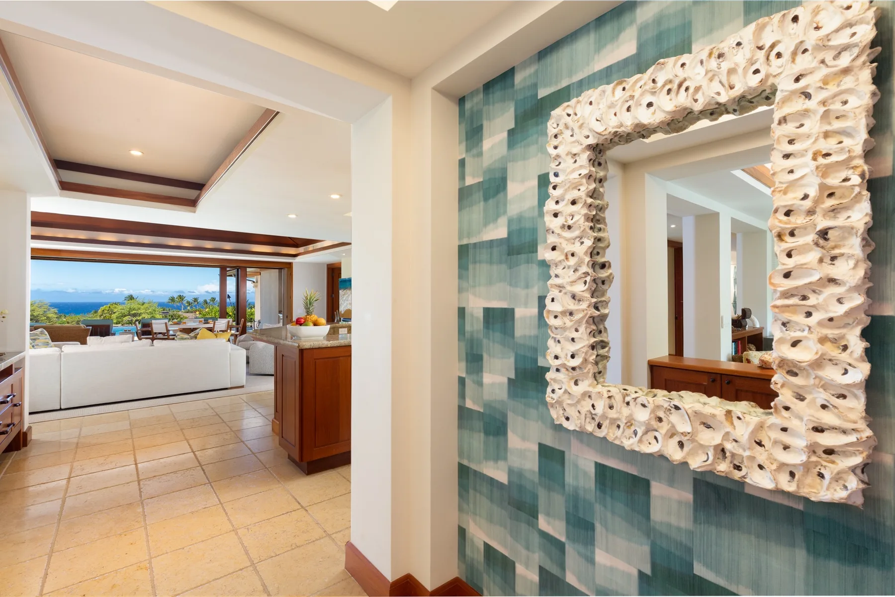 A tiled hallway wall with a large decorative mirror overlooks a bright living area.