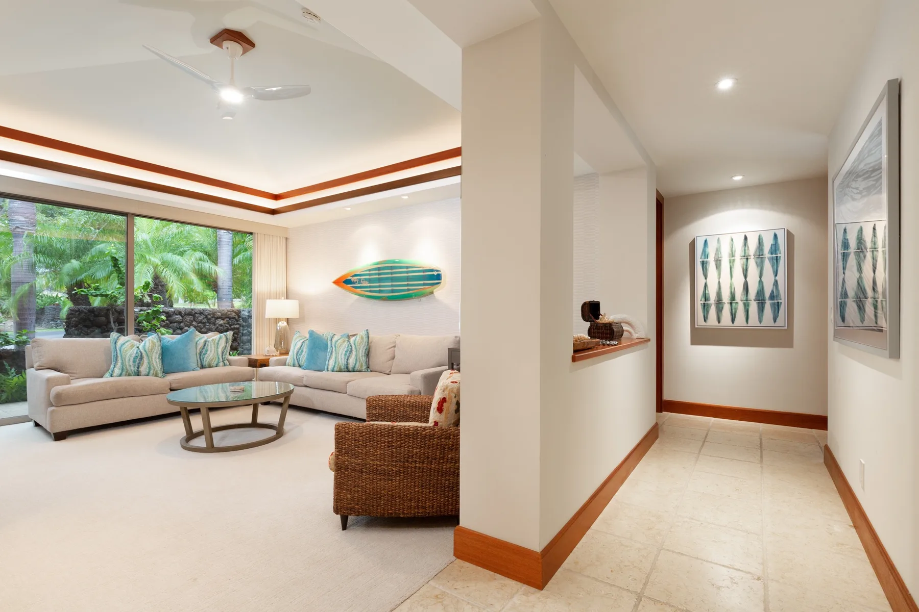 A bright living room opens onto a hallway, with seating and framed artwork.