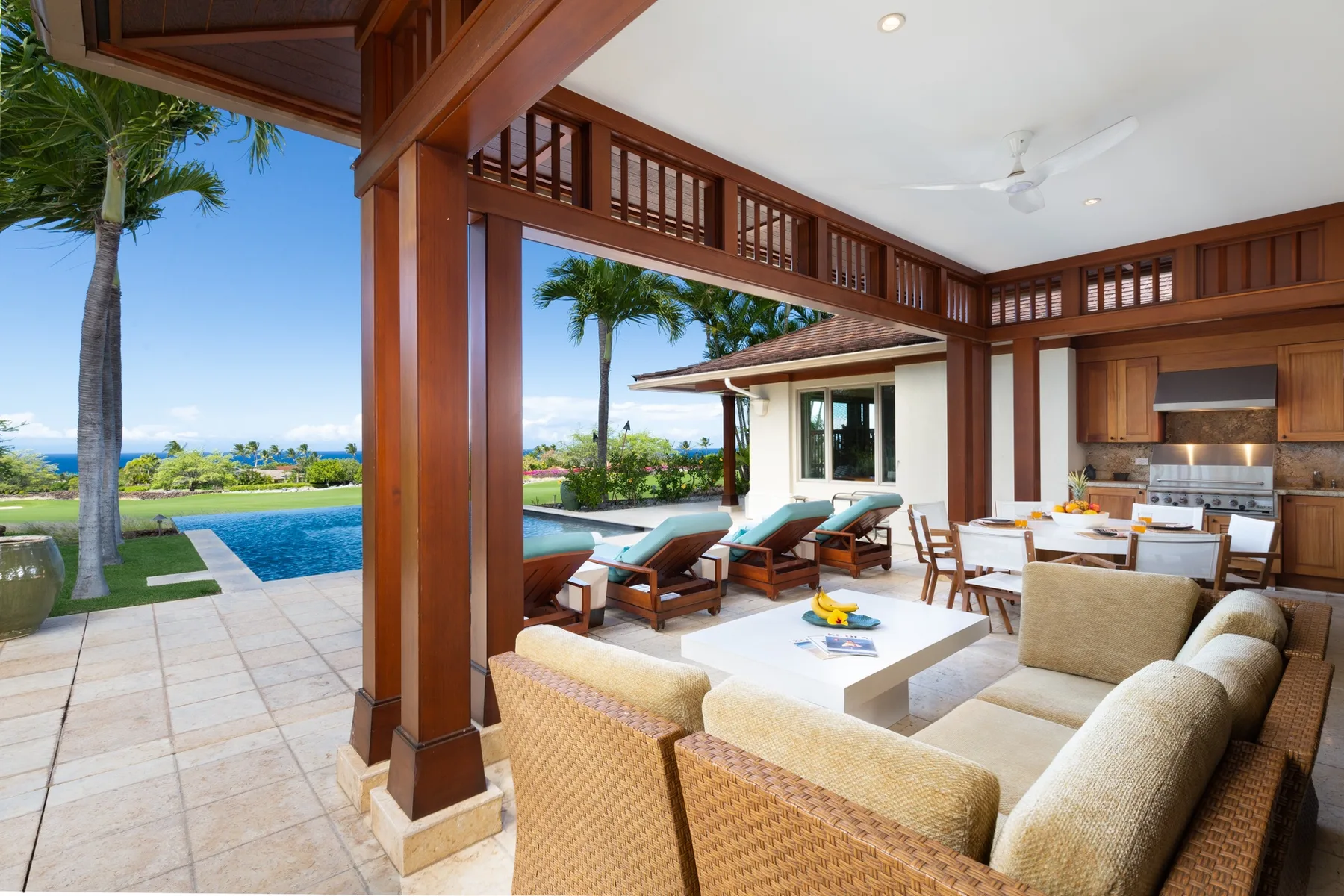 An open-air living and dining area overlooks a swimming pool and landscaped grounds.