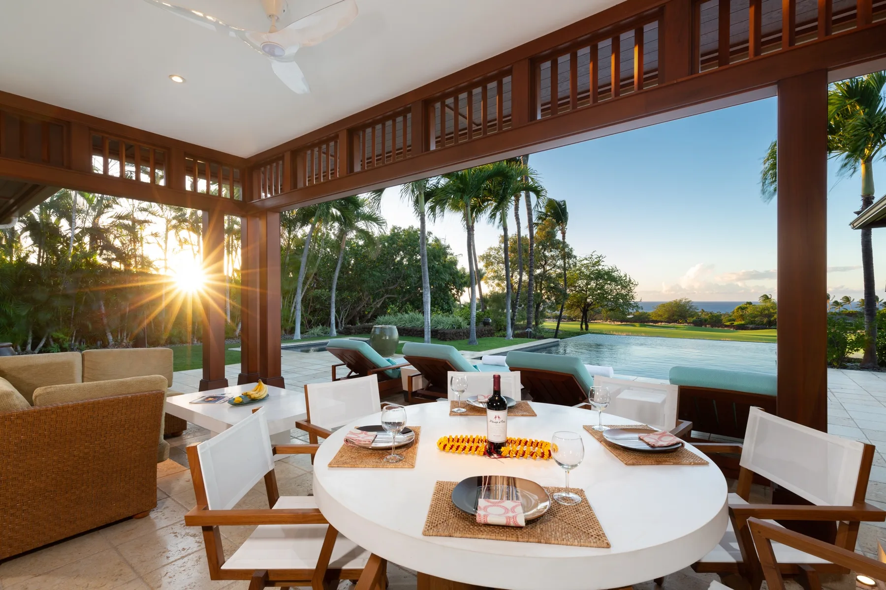A covered outdoor dining area overlooks a swimming pool and tropical greenery.