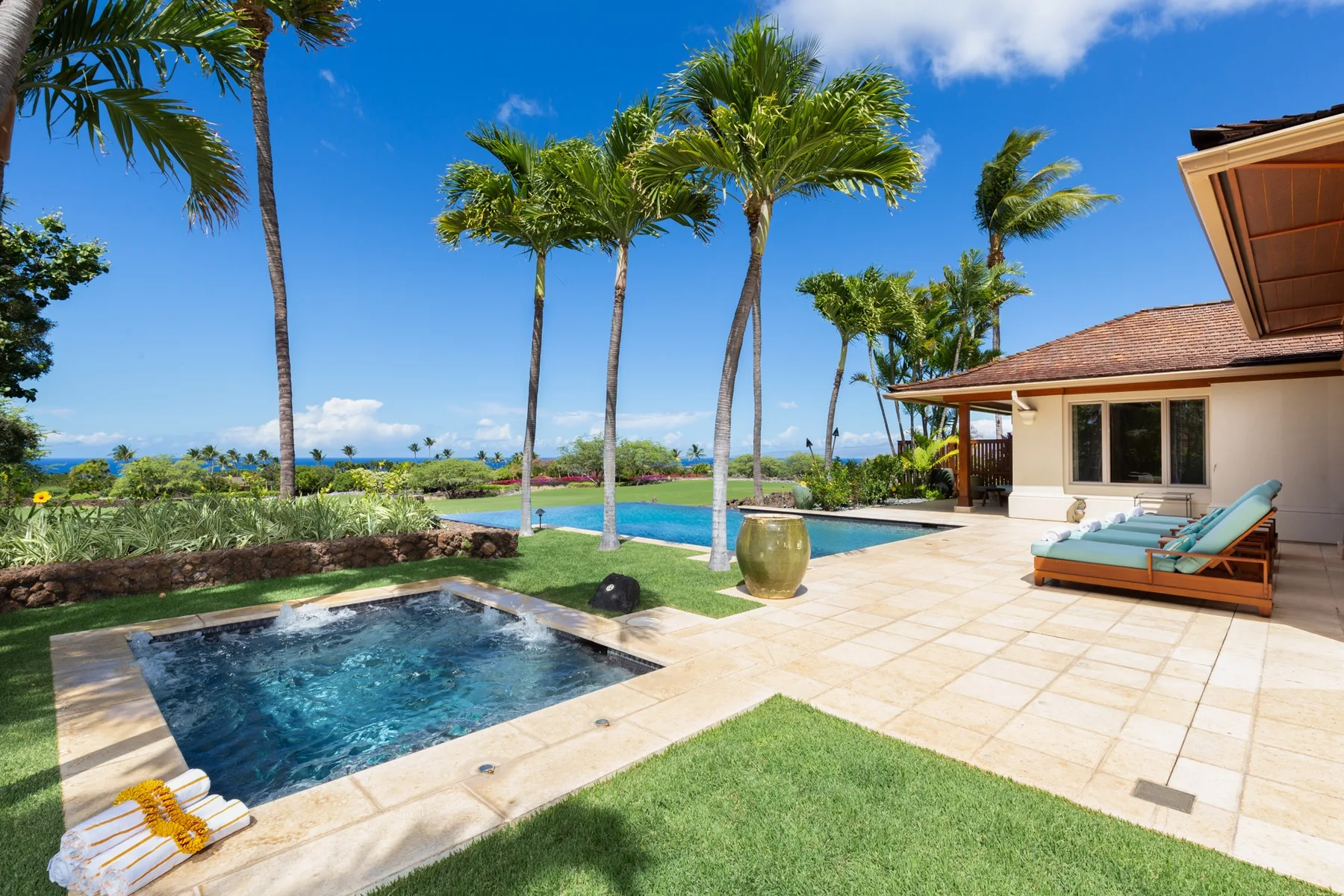 A sunny tropical courtyard has a small pool, a larger pool, and palm trees.