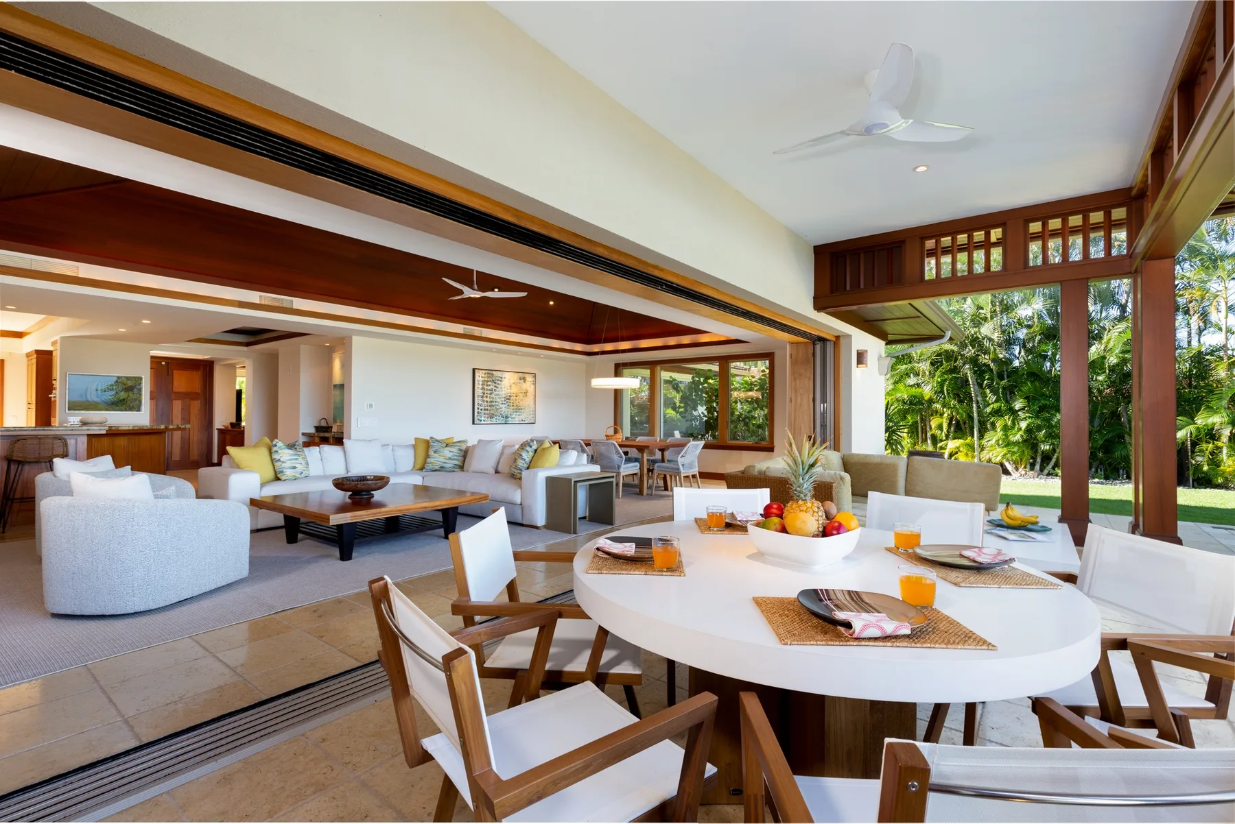 An open dining and living area with a round table and seating beside large windows.