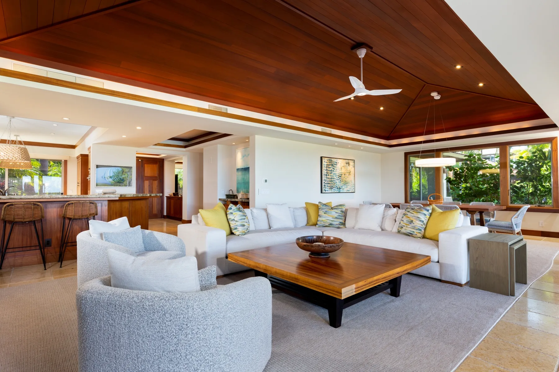 A spacious living room with white seating arranged around a wooden coffee table.