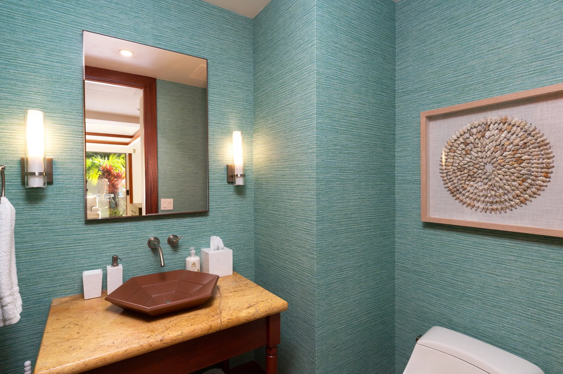 A bathroom with a vessel sink, wall mirror, and framed artwork.