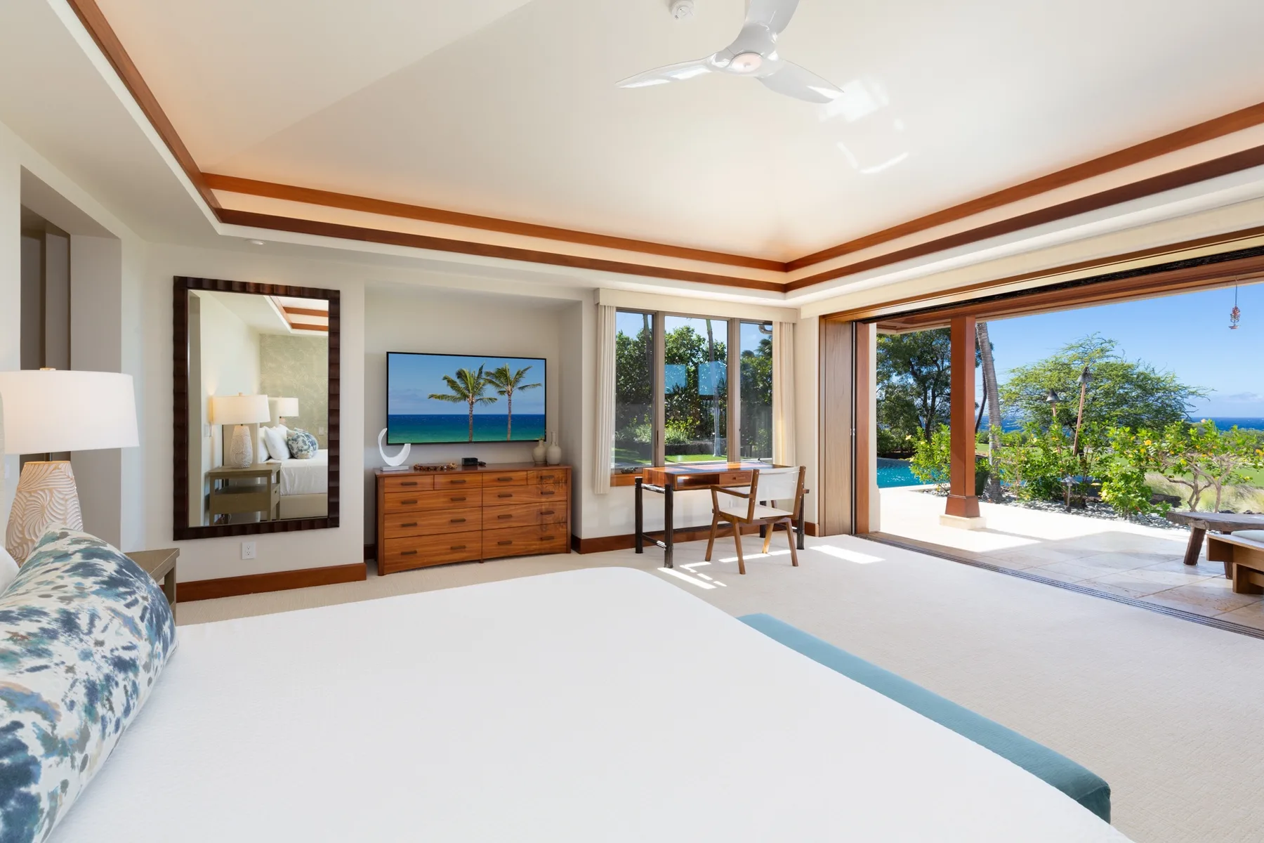 A bright bedroom opens onto a patio, with a bed and a view of greenery.