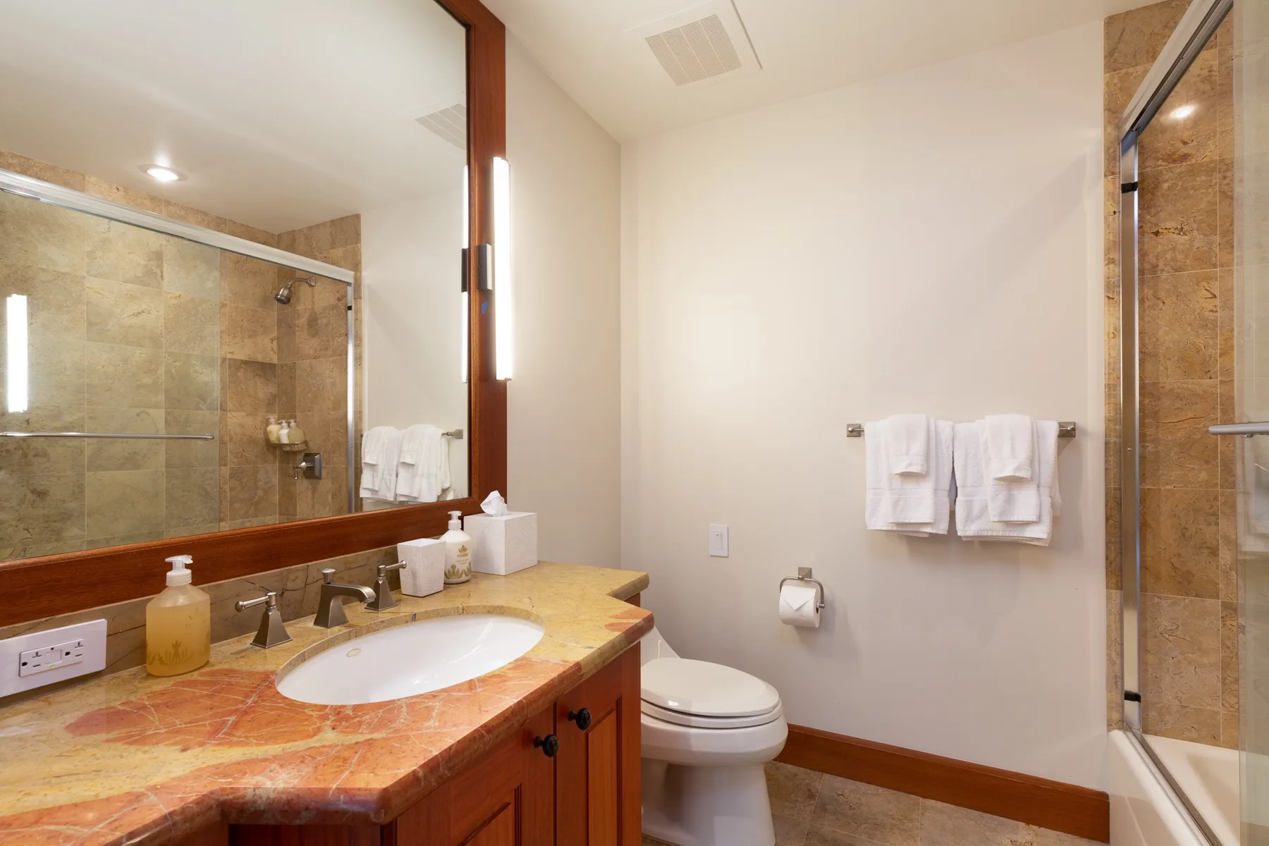 A bathroom with a vanity, toilet, and glass-enclosed shower.
