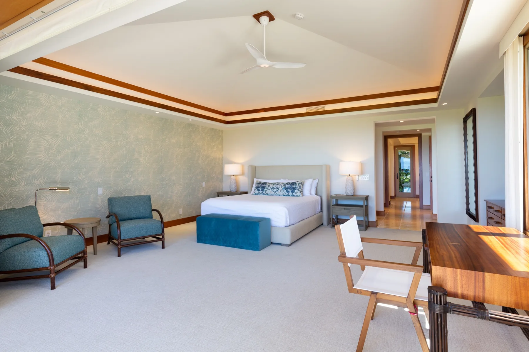 A spacious bedroom with a bed, seating, and a wooden dining table.