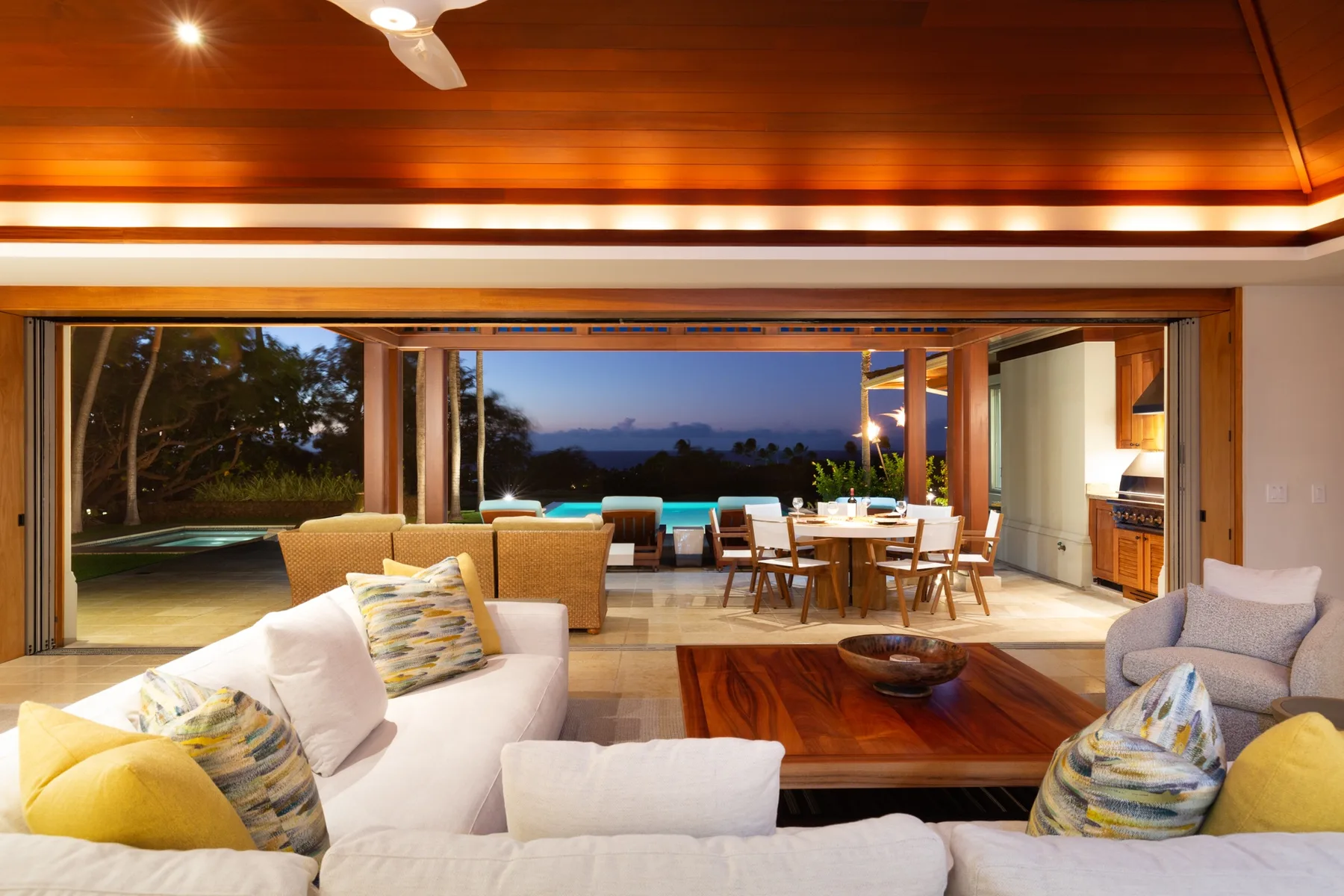 An open living and dining area looks out through wide doors to a patio at dusk.