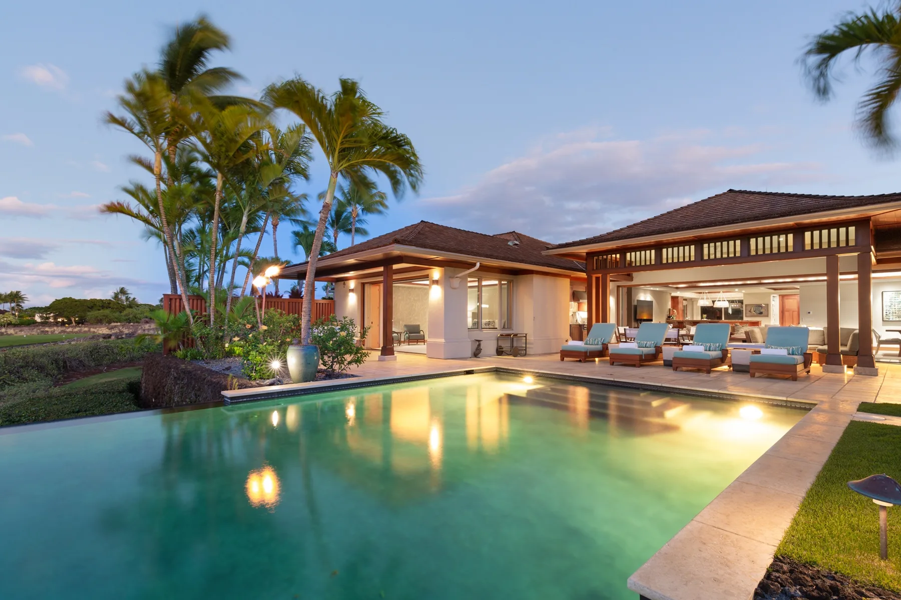 A resort-style building and outdoor swimming pool are illuminated at dusk.