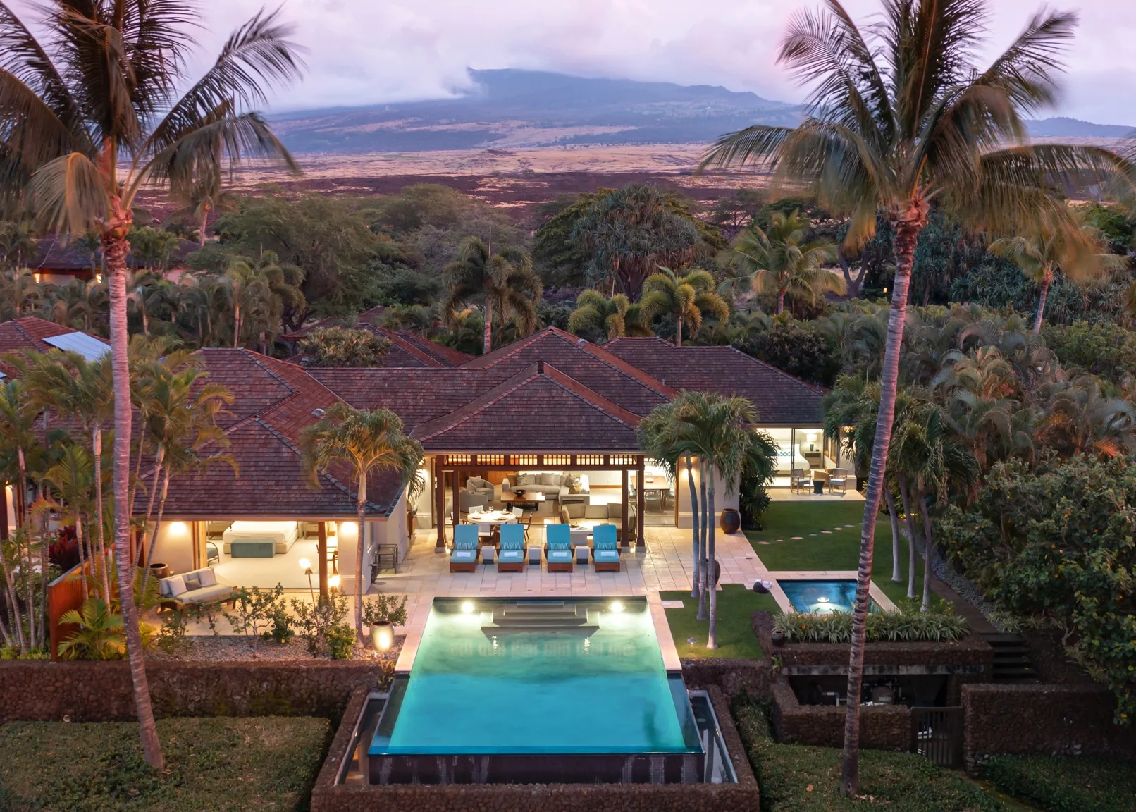 A resort-style property with a swimming pool, palm trees, and a distant landscape.