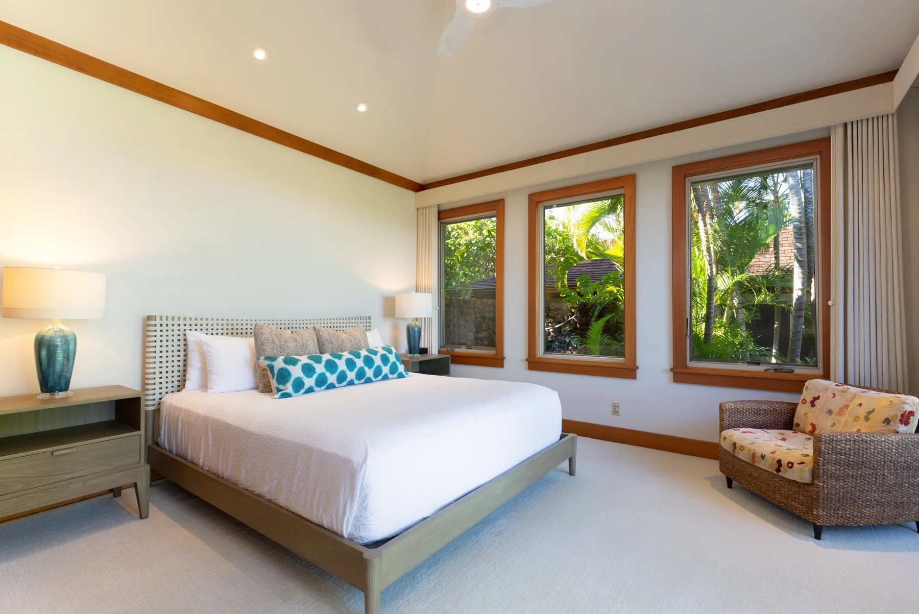 A bright bedroom with a bed and large windows overlooking greenery.